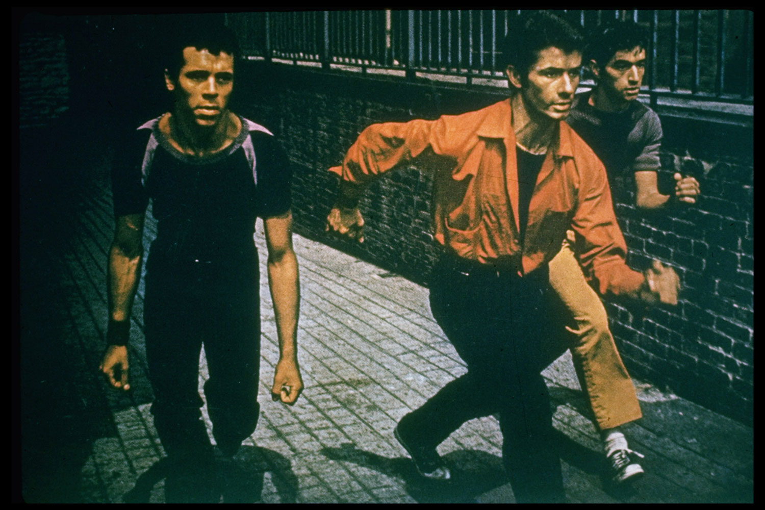 Bernardo (George Chakiris, center) leads gang, the Sharks, in a finger-snapping, crouching invasion of the turf of their rivals, the Jets.