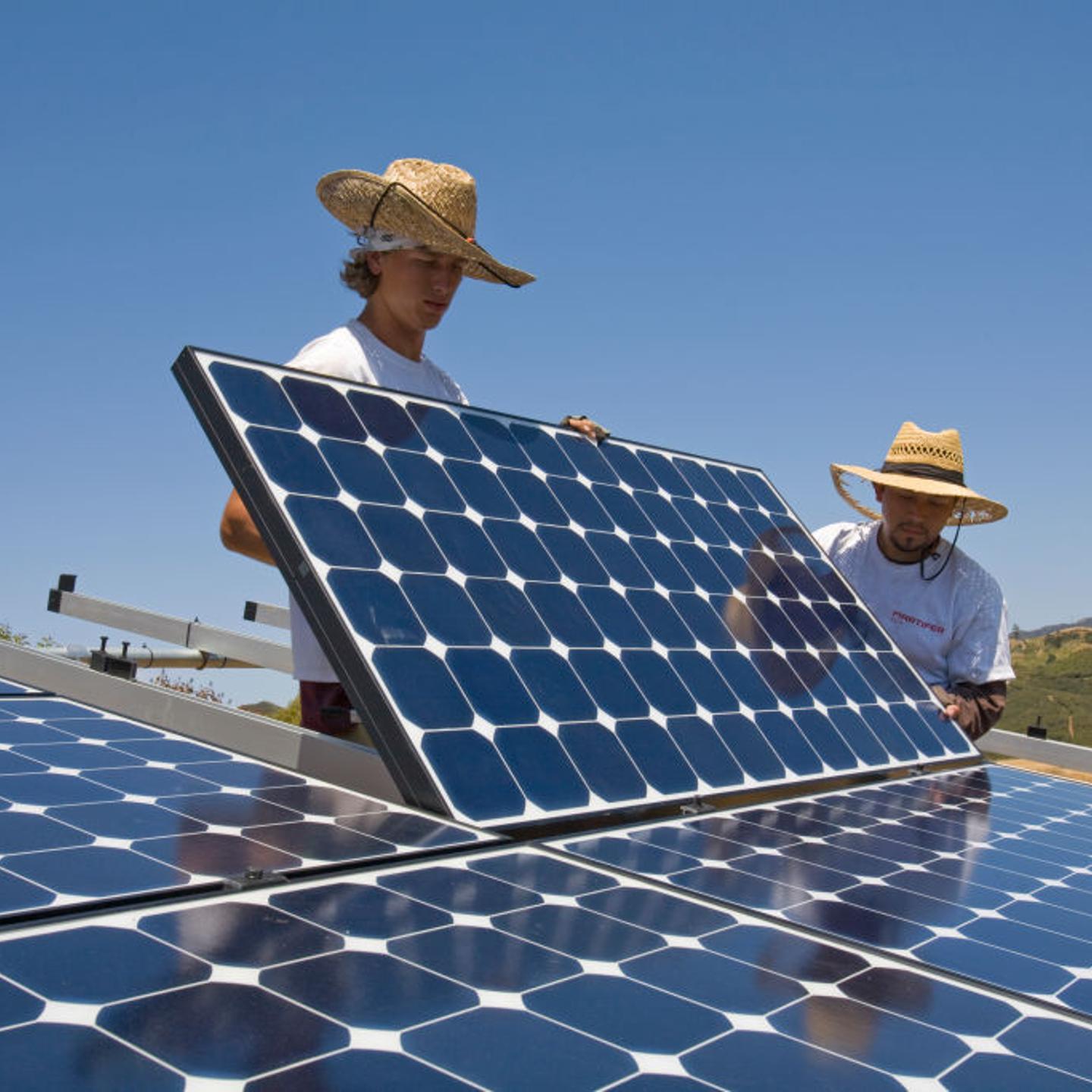 Green workers install a residential grid-tied solar array on a hillside in Malibu, California, USA.