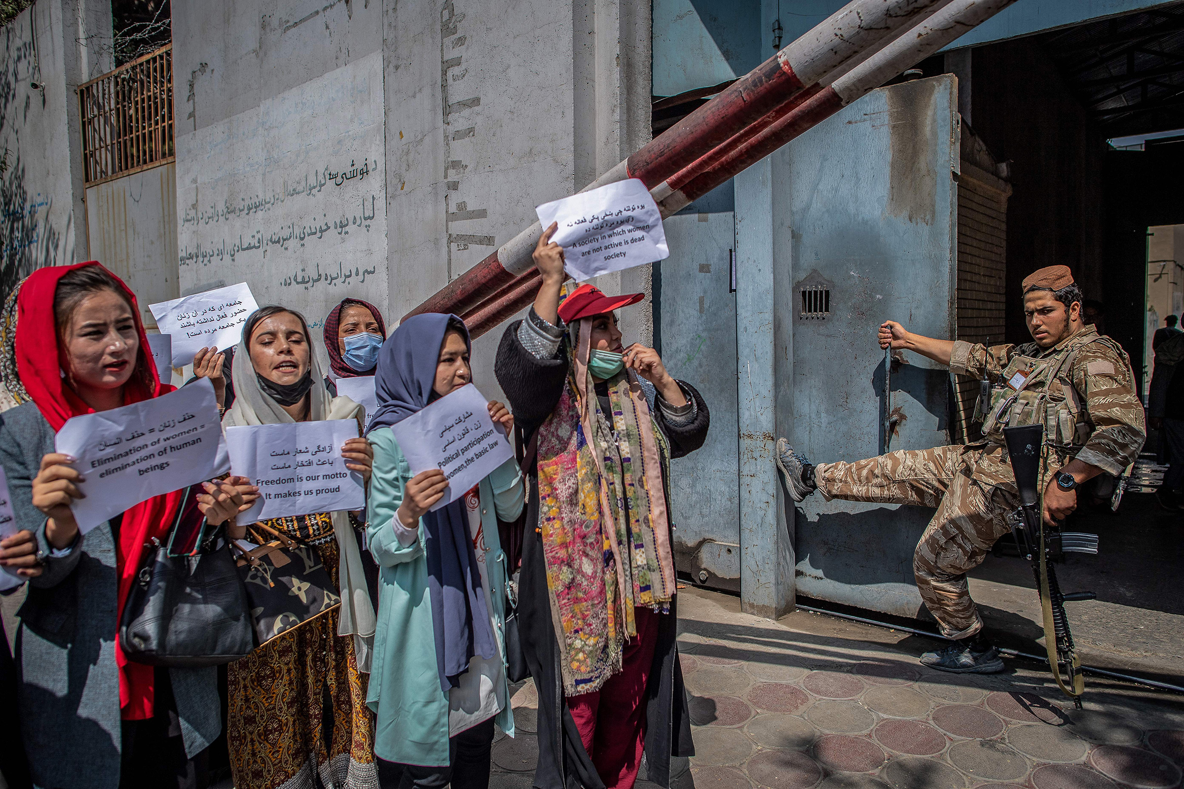 A Taliban fighter watches as Afghan women hold placards during a demonstration demanding better rights for women in front of the former Ministry of Women Affairs in Kabul on Sept. 19, 2021. 