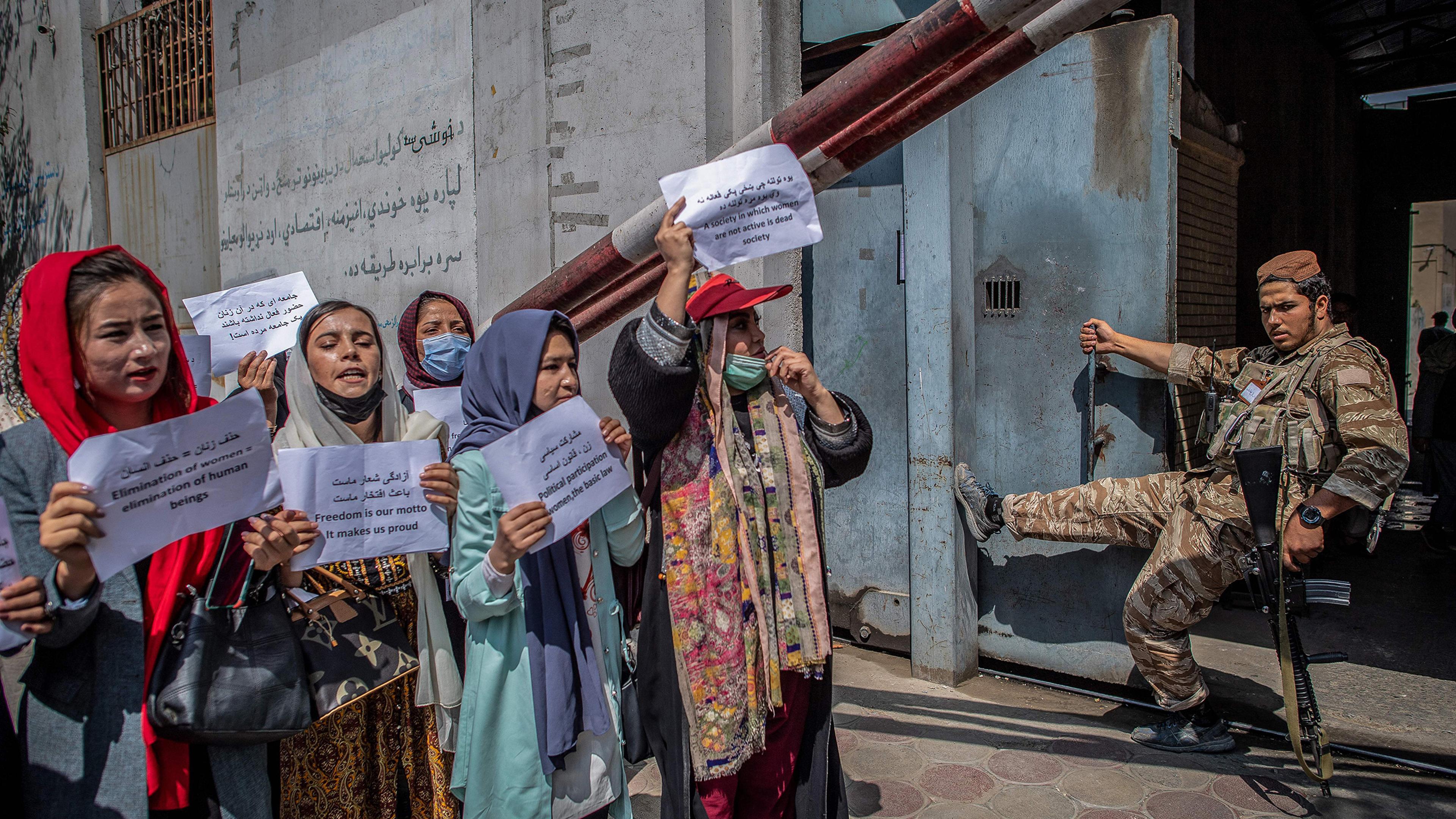 A Taliban fighter watches as Afghan women hold placards during a demonstration demanding better rights for women in front of the former Ministry of Women Affairs in Kabul on Sept. 19, 2021.