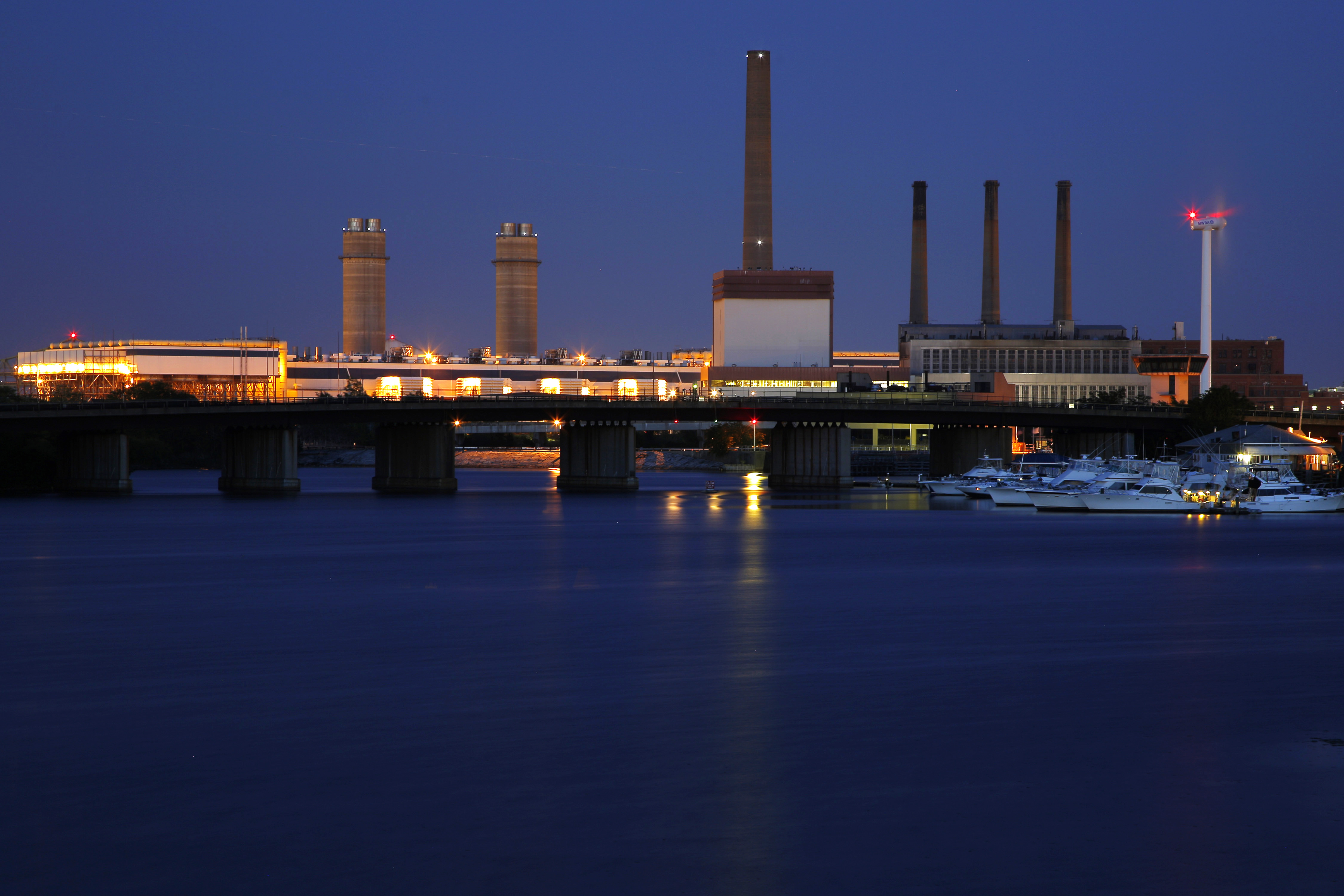 A Massachusetts Water Resources Authority wind turbine turns beside a 2002 megawatt fossil fuel power plant in Charlestown