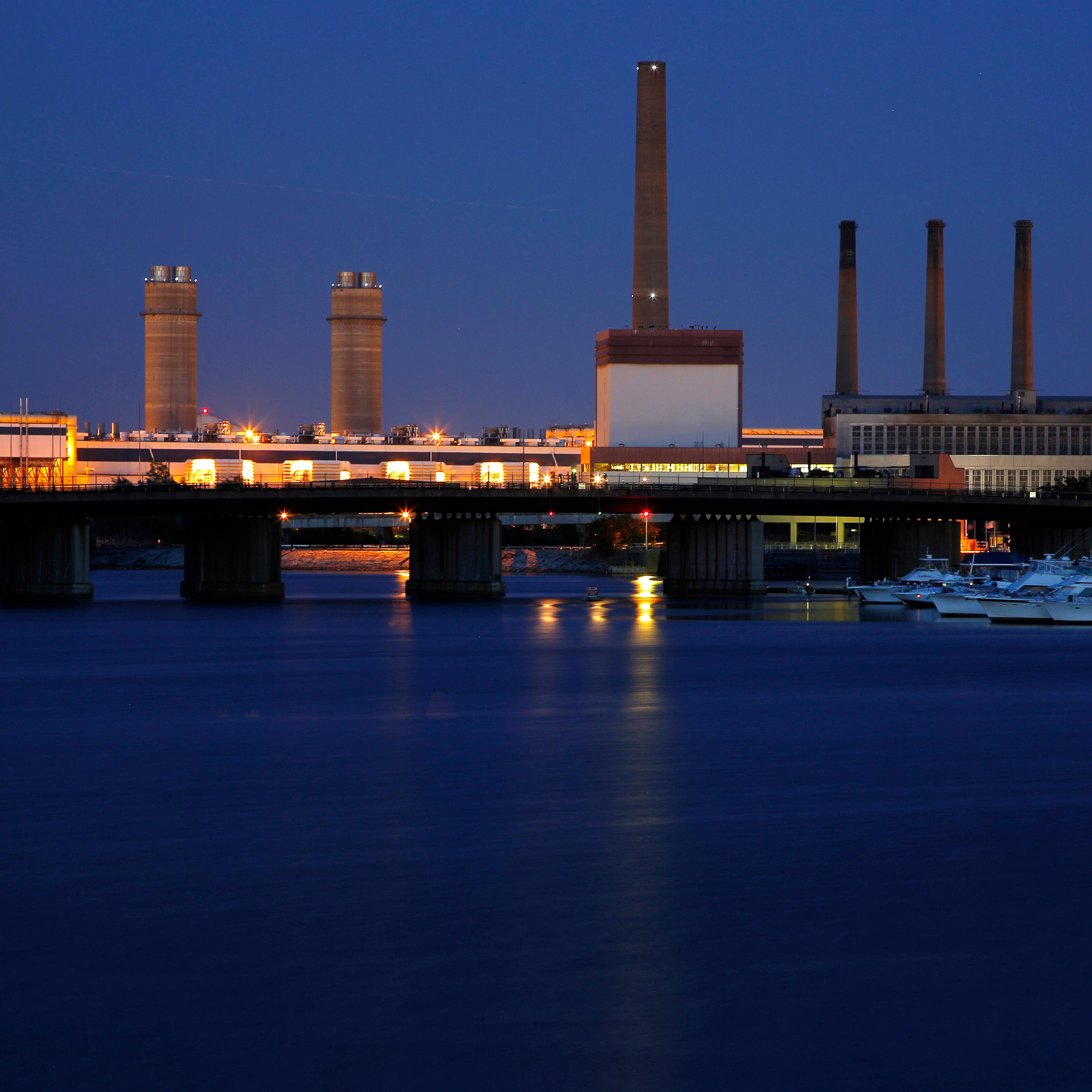 A Massachusetts Water Resources Authority wind turbine turns beside a 2002 megawatt fossil fuel power plant in Charlestown
