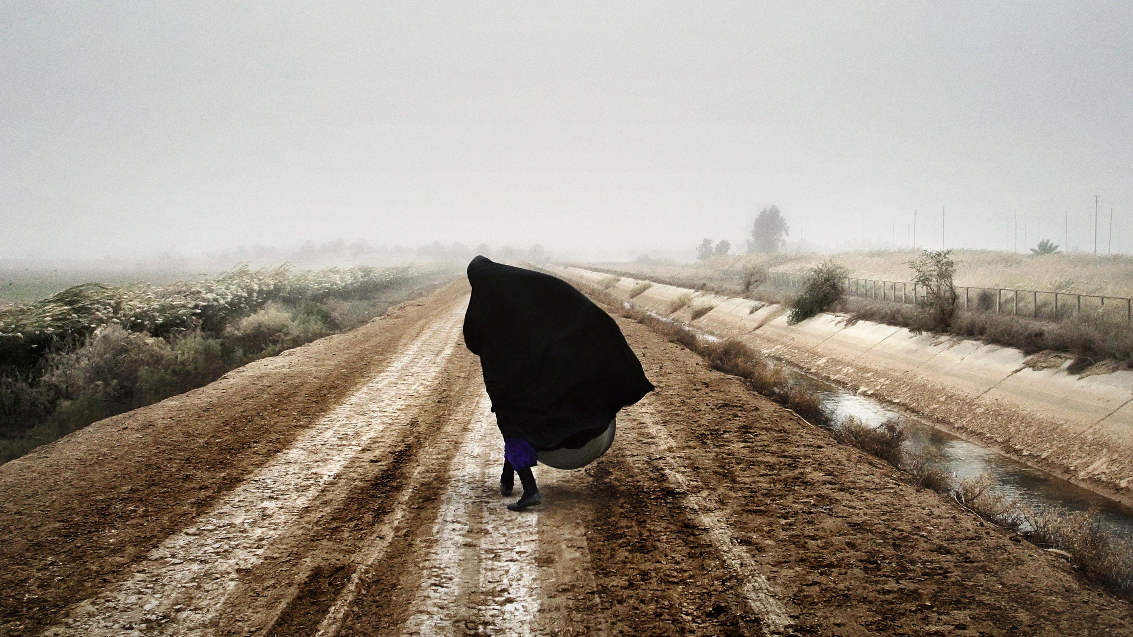 An Iraqi woman walks on a road south of Baghdad, Dec. 20, 2002, prior to the U.S. invasion in March 2003.