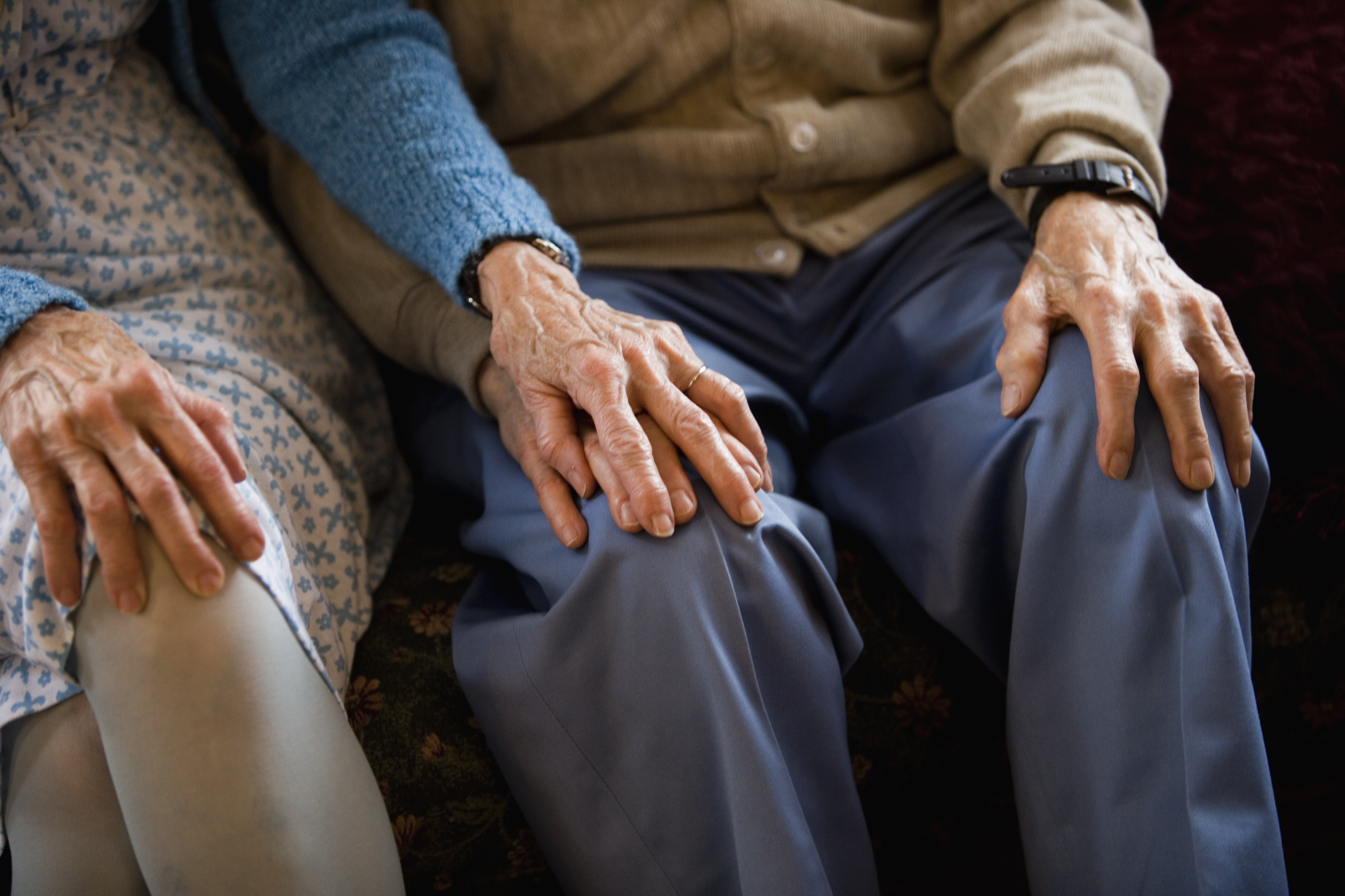 Close-up of senior couple holding hands while sitting