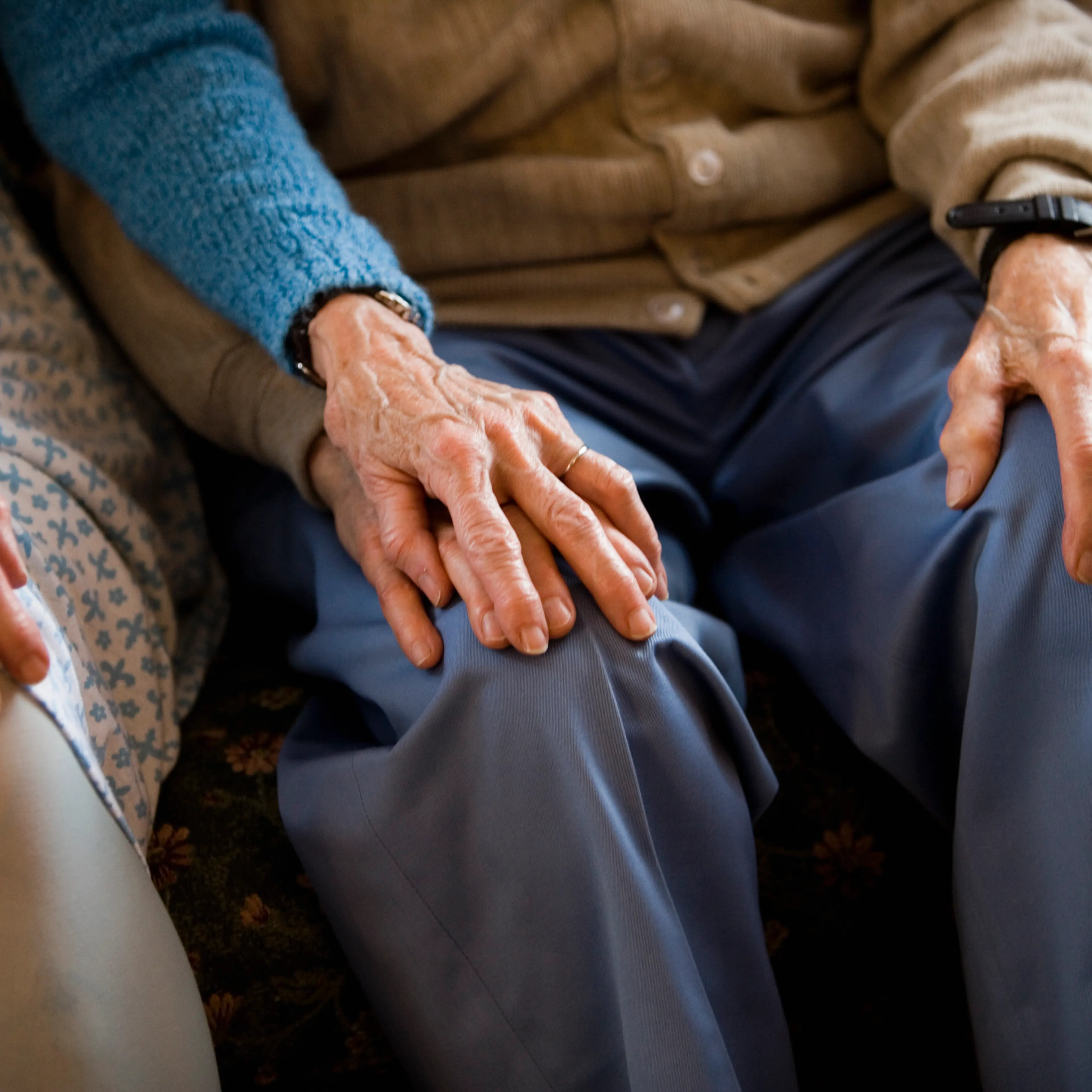 Close-up of senior couple holding hands while sitting