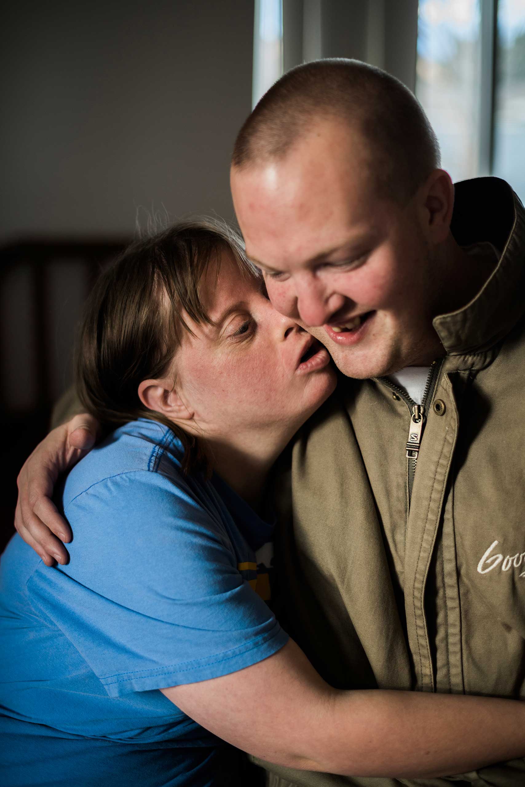 Krysta and Nathaniel embrace as Krysta leans forward to kiss him.