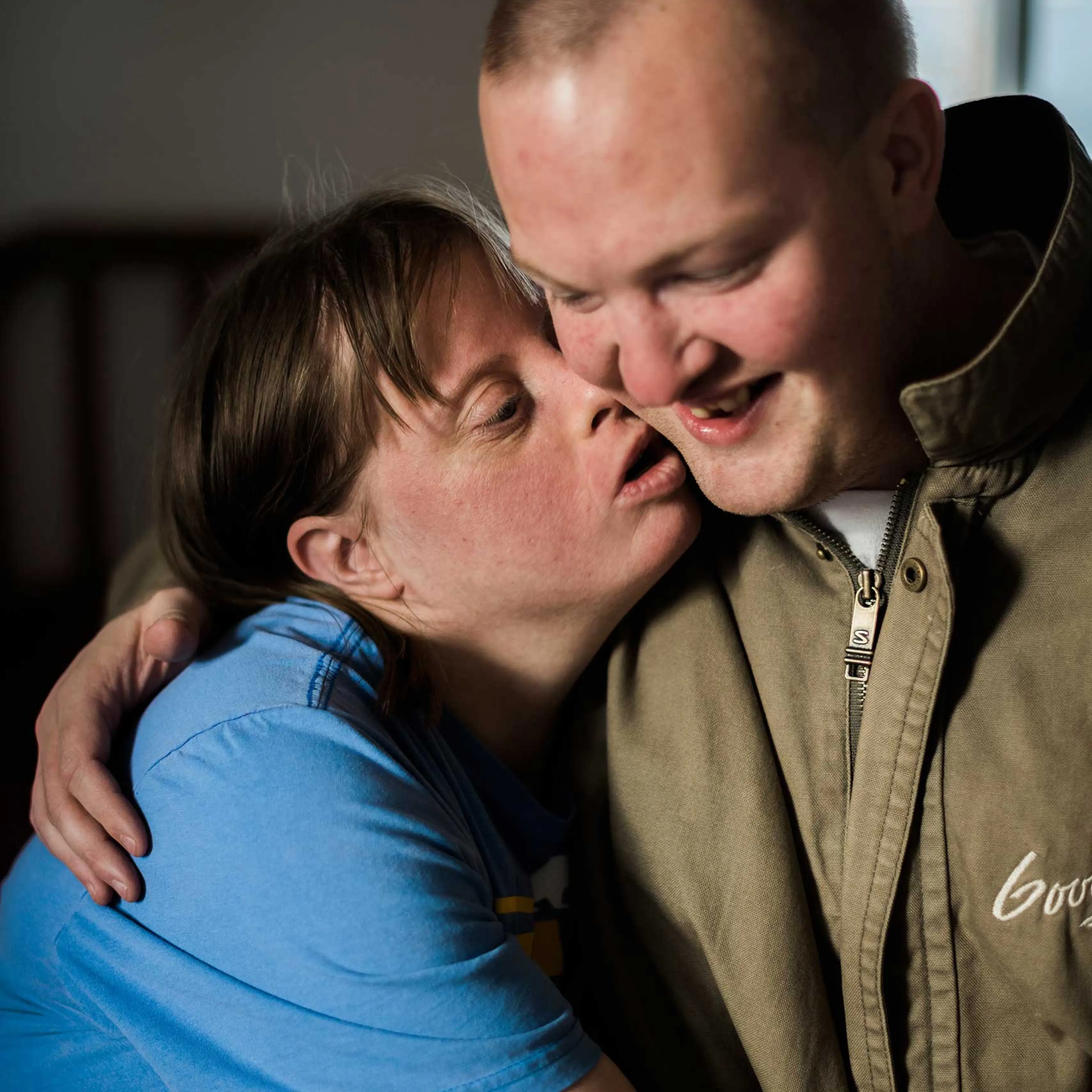 Krysta and Nathaniel embrace as Krysta leans forward to kiss him.