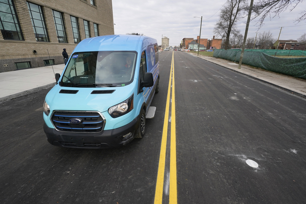 An electric van drives on a street with in-road wireless charging coils below the surface in Detroit, Nov. 29, 2023.