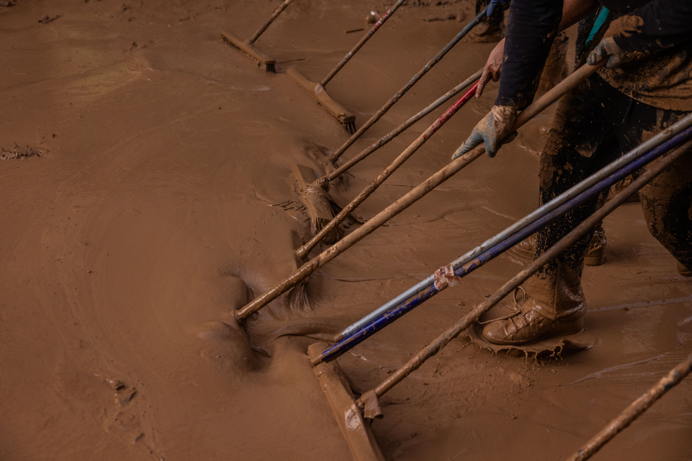 Volunteers work on Friday Nov. 1, 2024, to remove mud from the center of Paiporta, considered the ground zero of the devastating floods in the province of Valencia, Spain. Thousands of volunteers came from all over to help residents clean homes, business