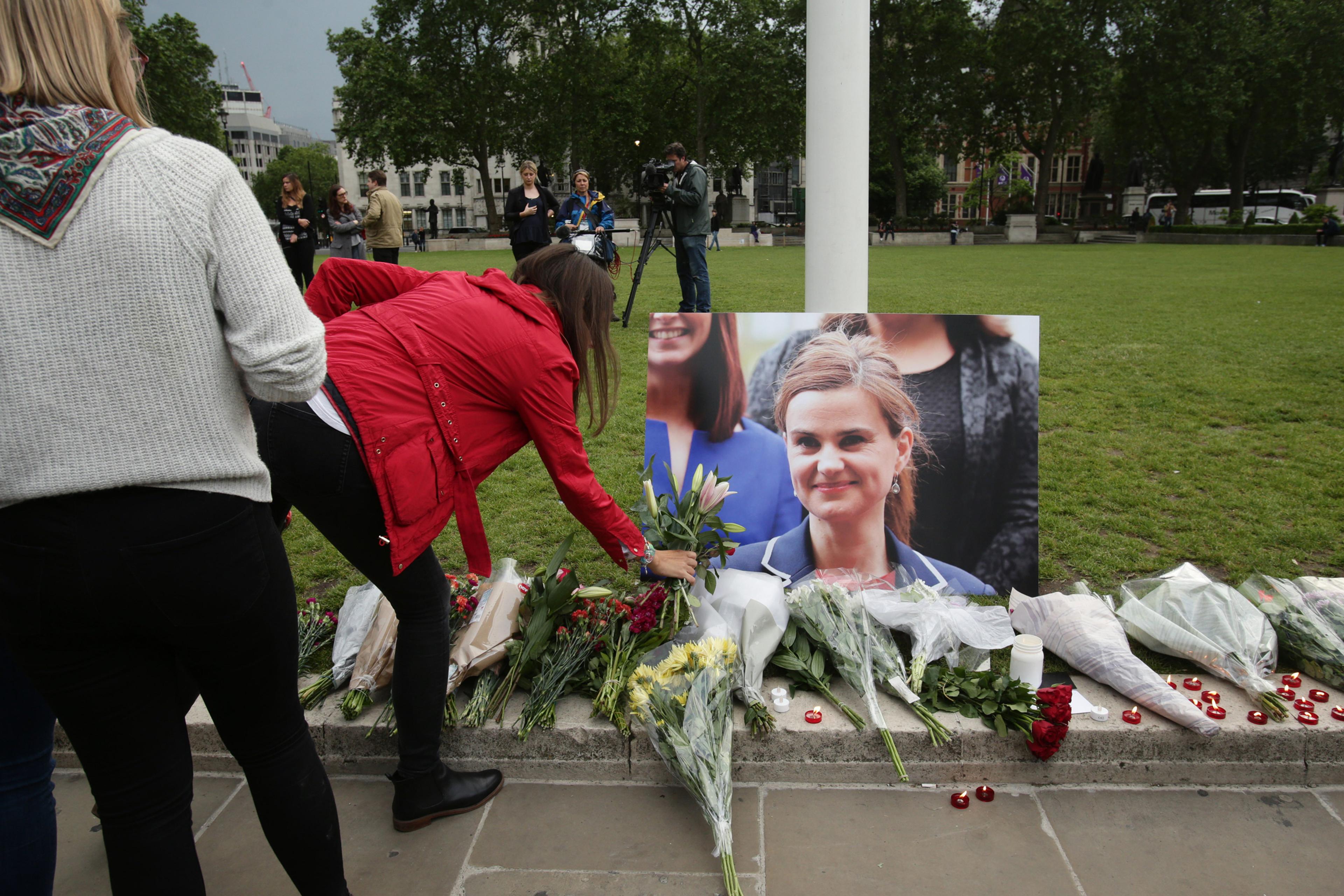 Jo Cox shooting. A woman lays some flowers at Parliament Square opposite the Palace of Westminster, central London, in tribute to Labour MP Jo Cox, who died after being shot and stabbed in the street outside her constituency advice surgery in Birstall, W