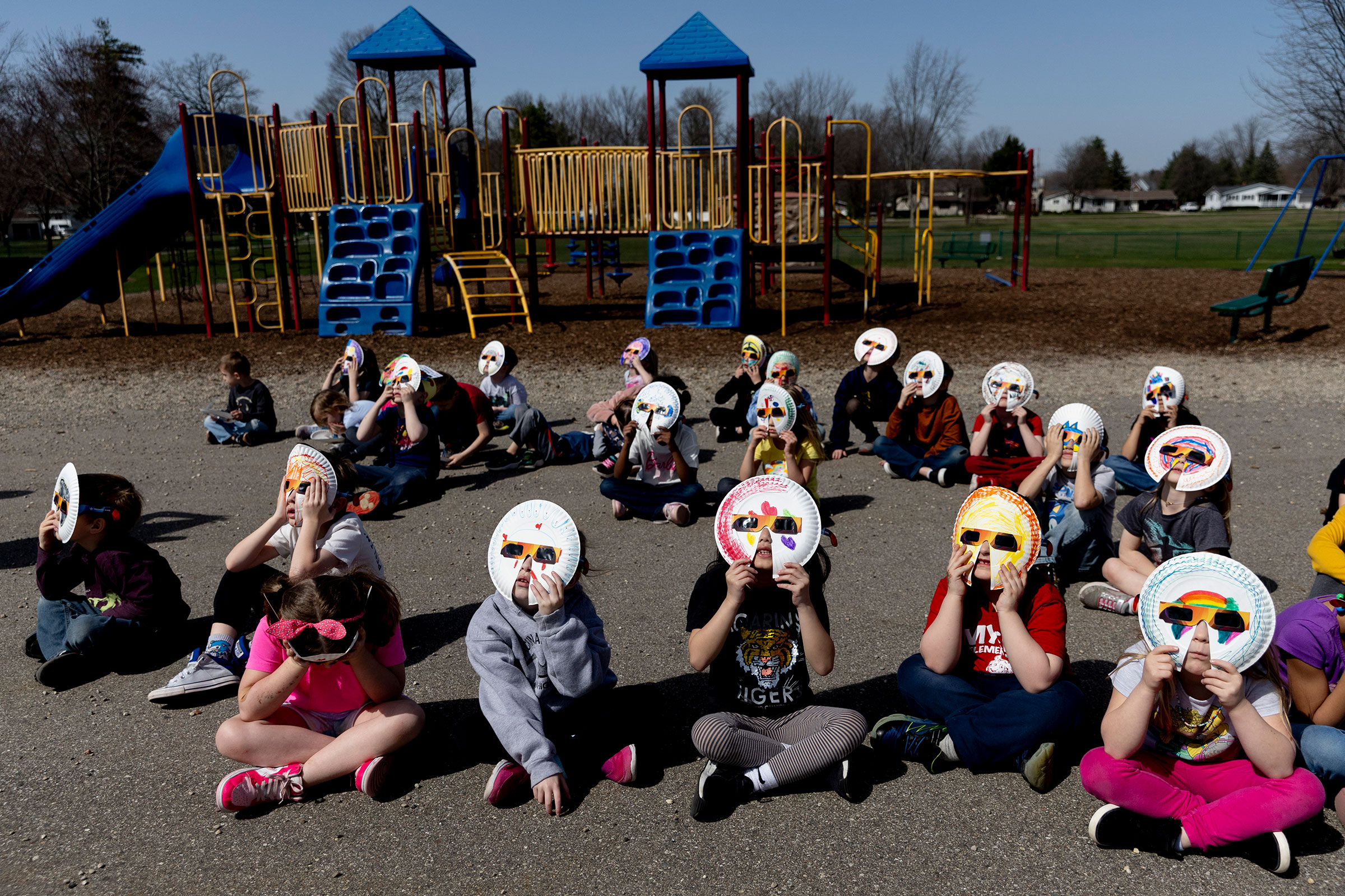 Kindergartners at Myers Elementary School in Grand Blanc, Mich., use paper-plate glasses to safely watch the solar eclipse on April 8.