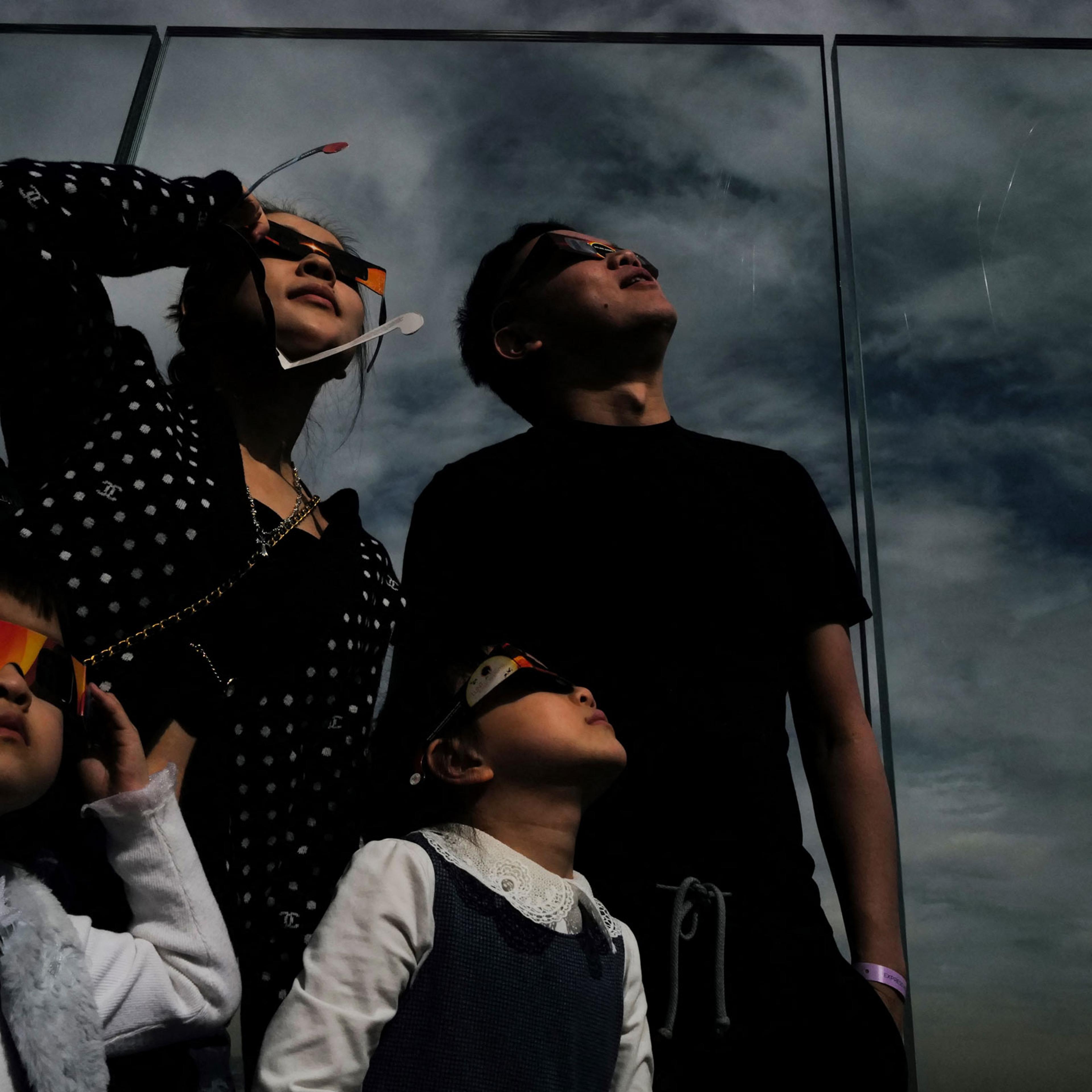 A woman looks toward the sky at the Edge at Hudson Yards observation deck during a solar eclipse, in New York City.