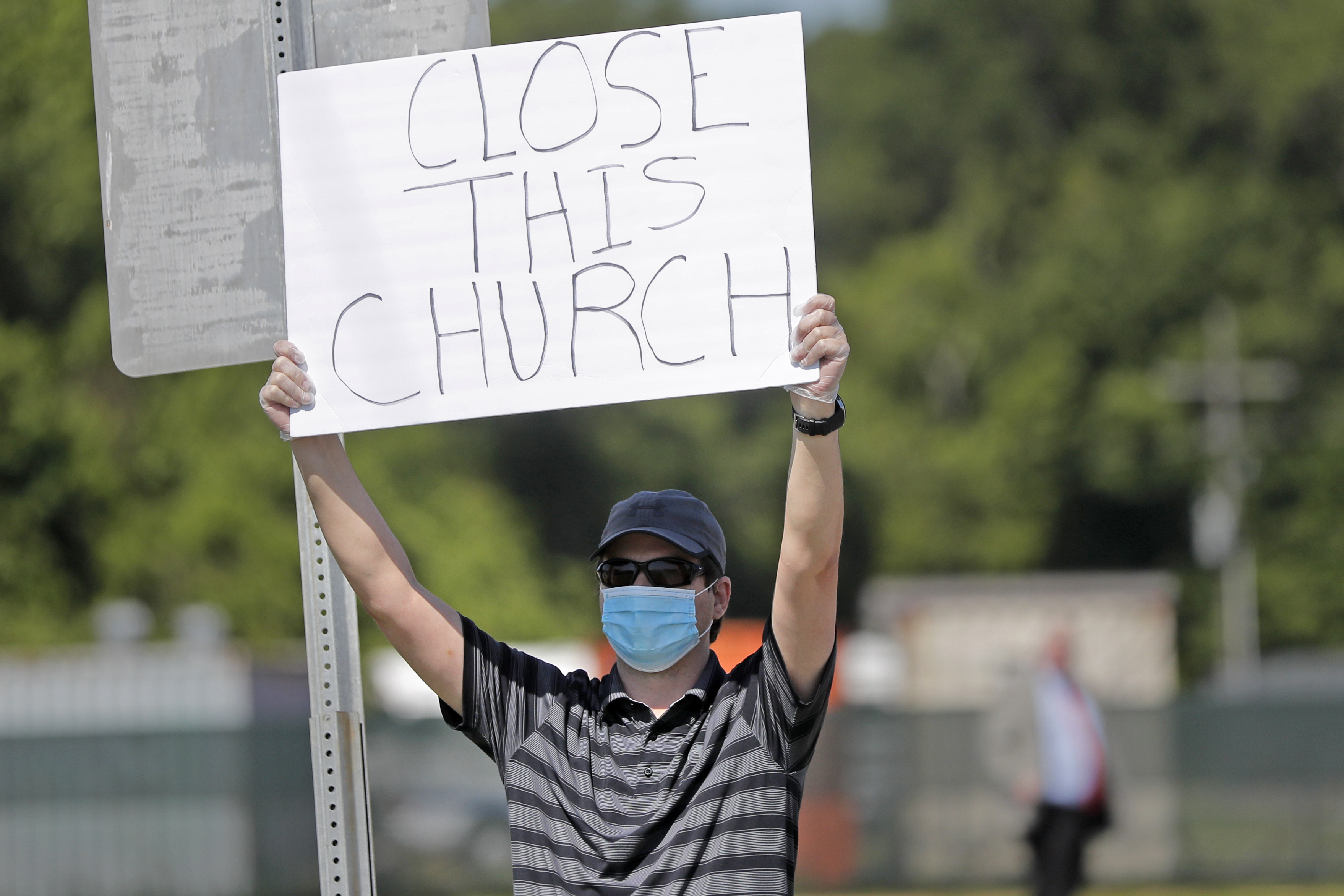 Protestor Trey Bennett holds a sign towards members of the Life Tabernacle Church
