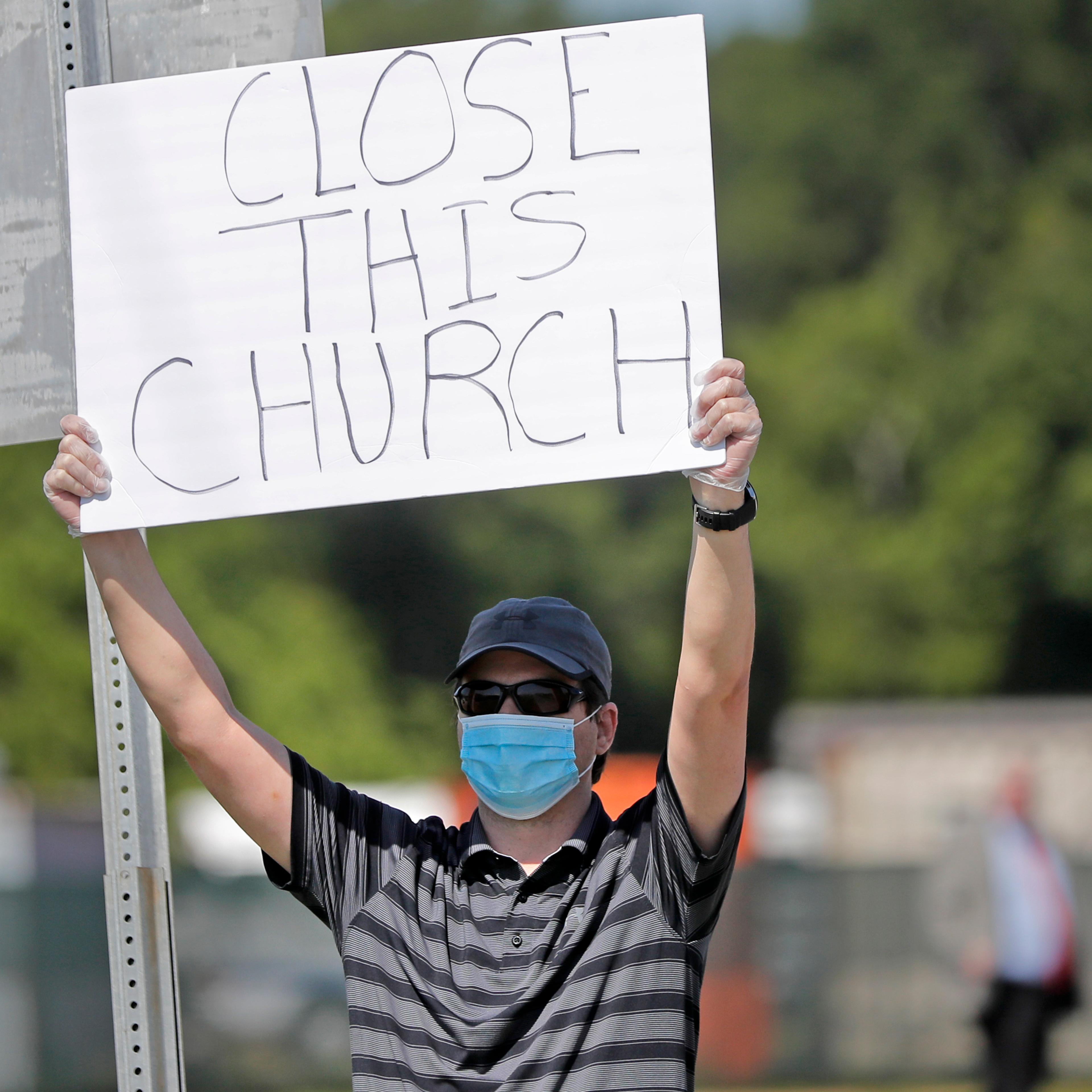 Protestor Trey Bennett holds a sign towards members of the Life Tabernacle Church