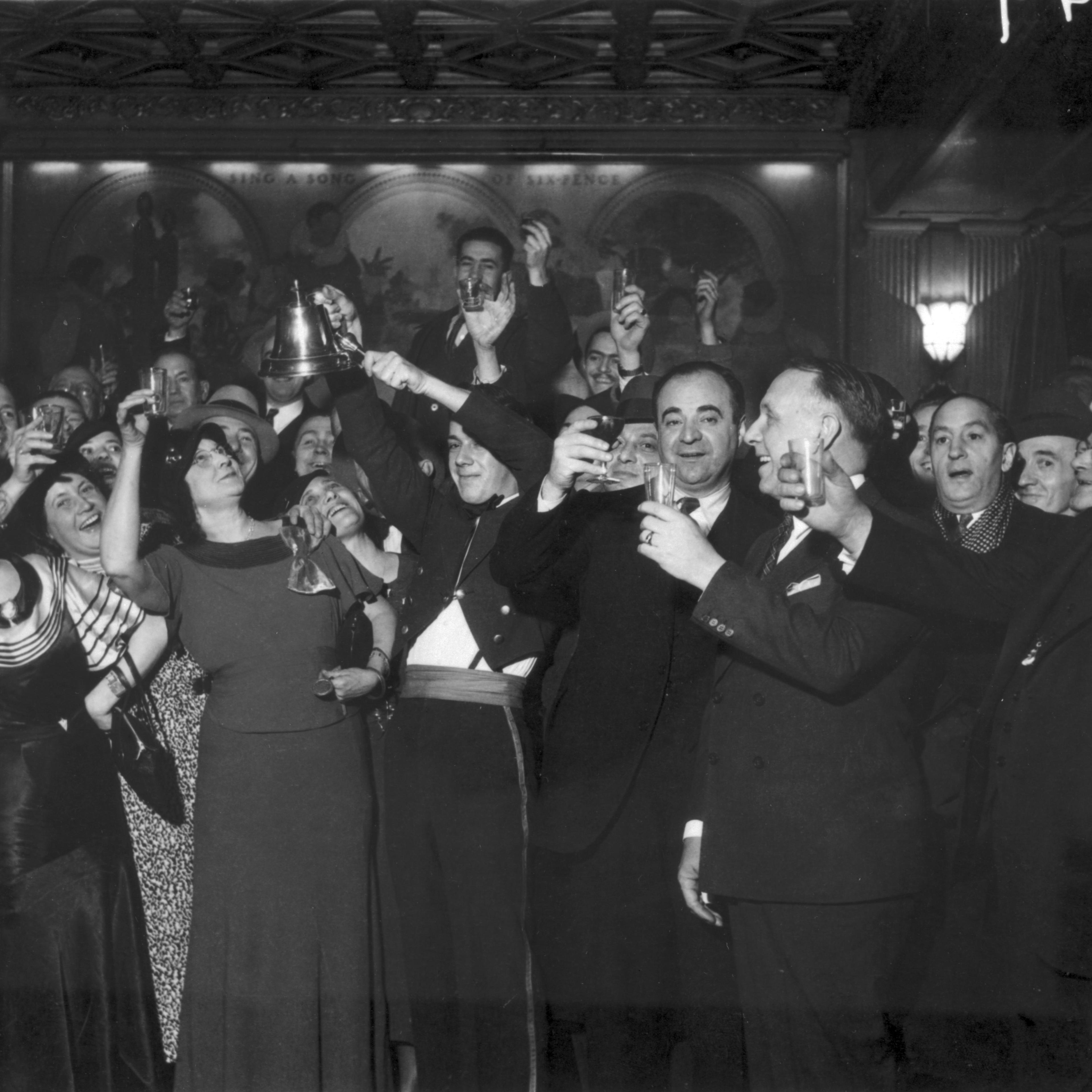 Men and women in a a bar raising glasses celebrating prohibition's end