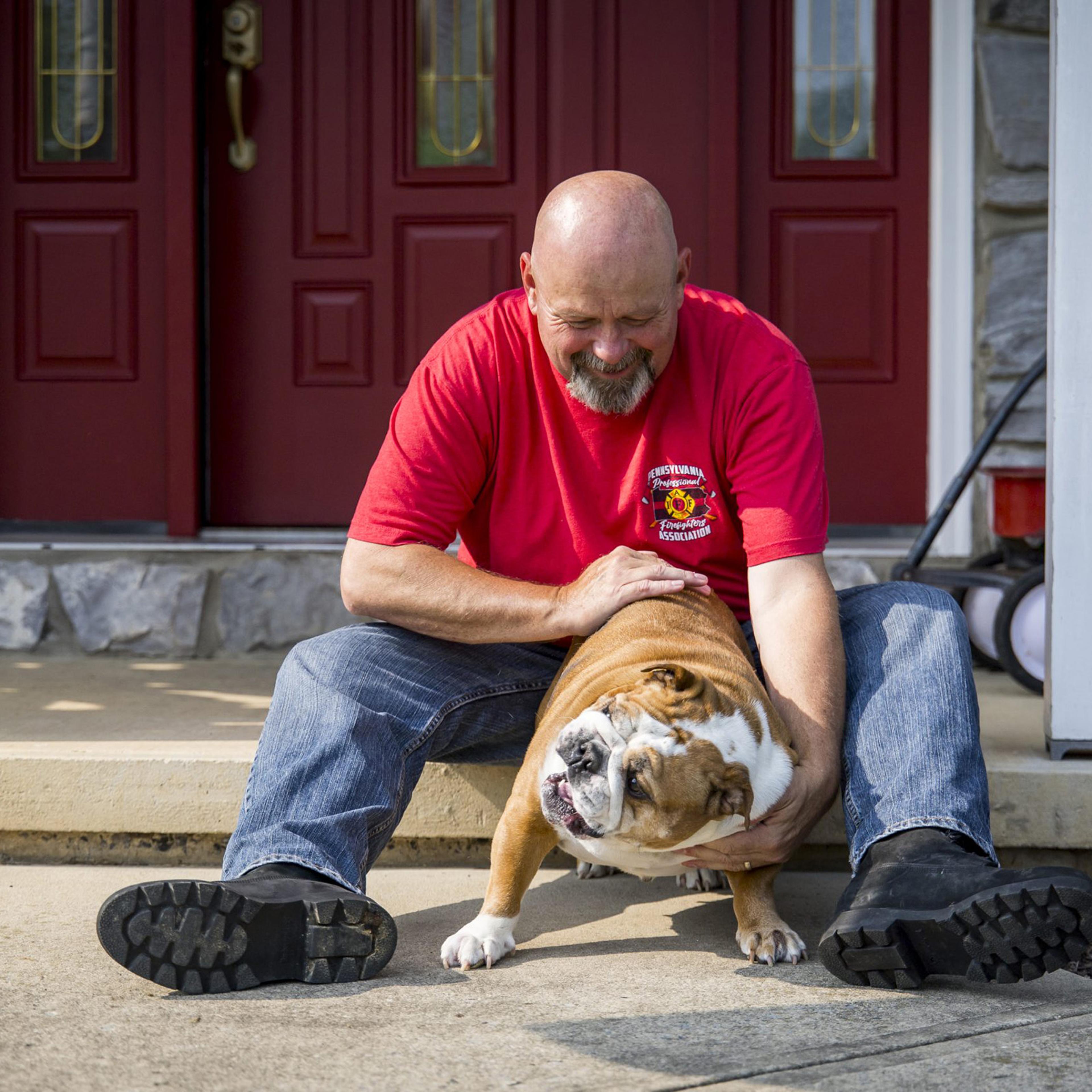 Bob Brooks with a bulldog on a front porch.