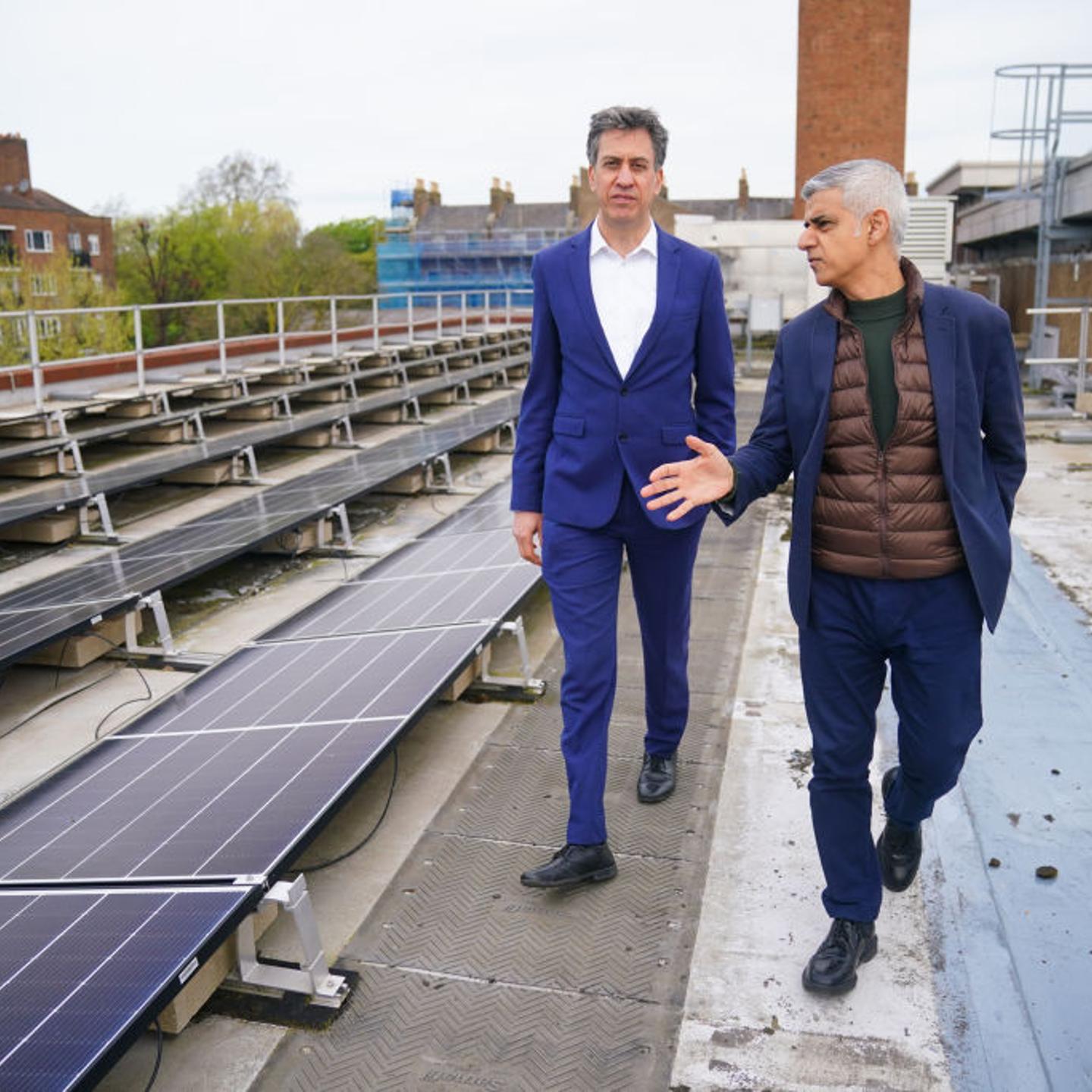 Mayor of London Sadiq Khan (right) and shadow energy secretary Ed Miliband, walk past solar panels installed on the roof of Stoke Newington School in north London, during a visit to announce a new climate action plan for London on April 12, 2024.