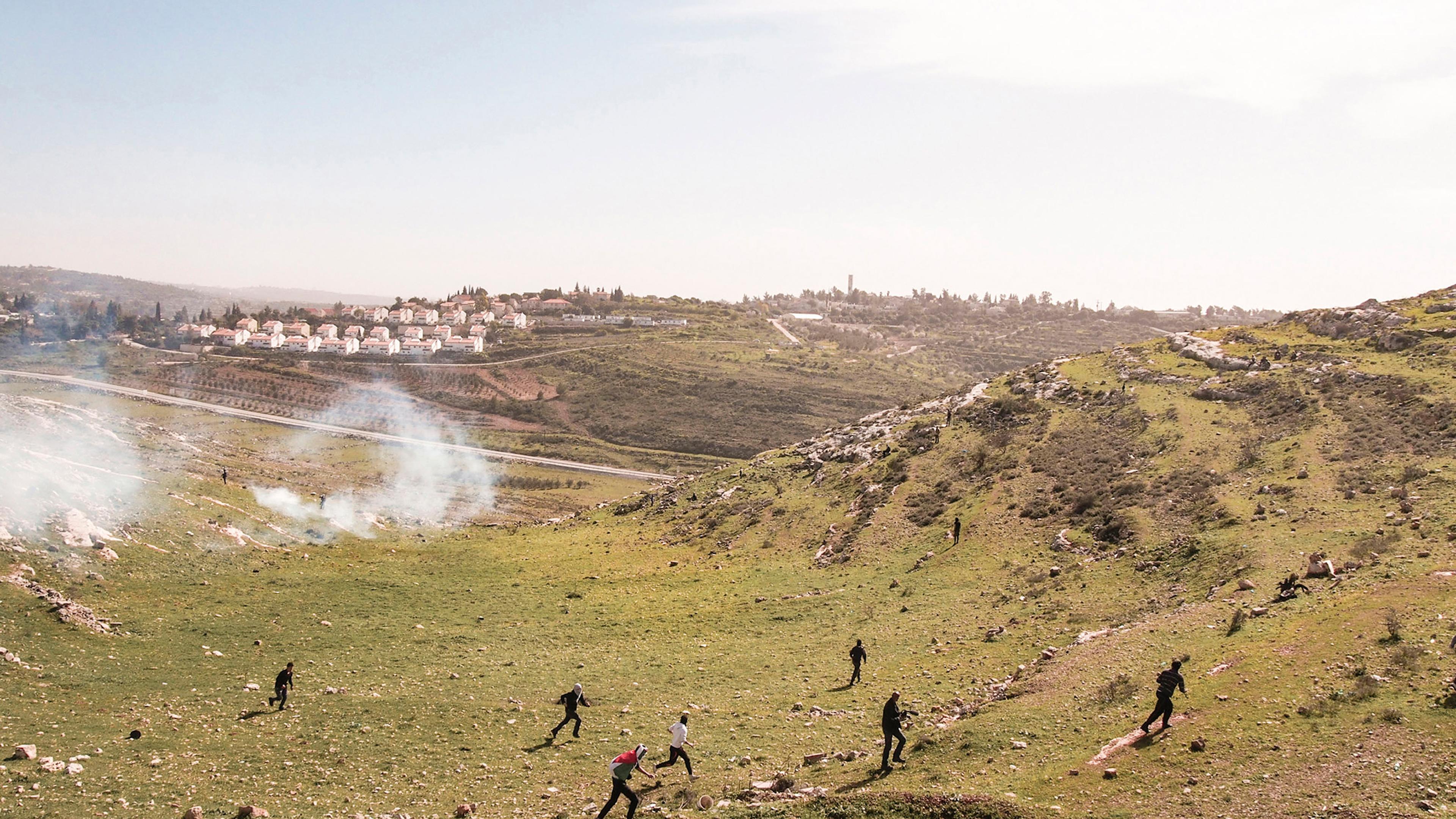 WEST BANK. Nabi Saleh. 2013. Palestinian protestors run from tear gas fired by Israeli soldiers at a weekly protest against the Israeli occupation.