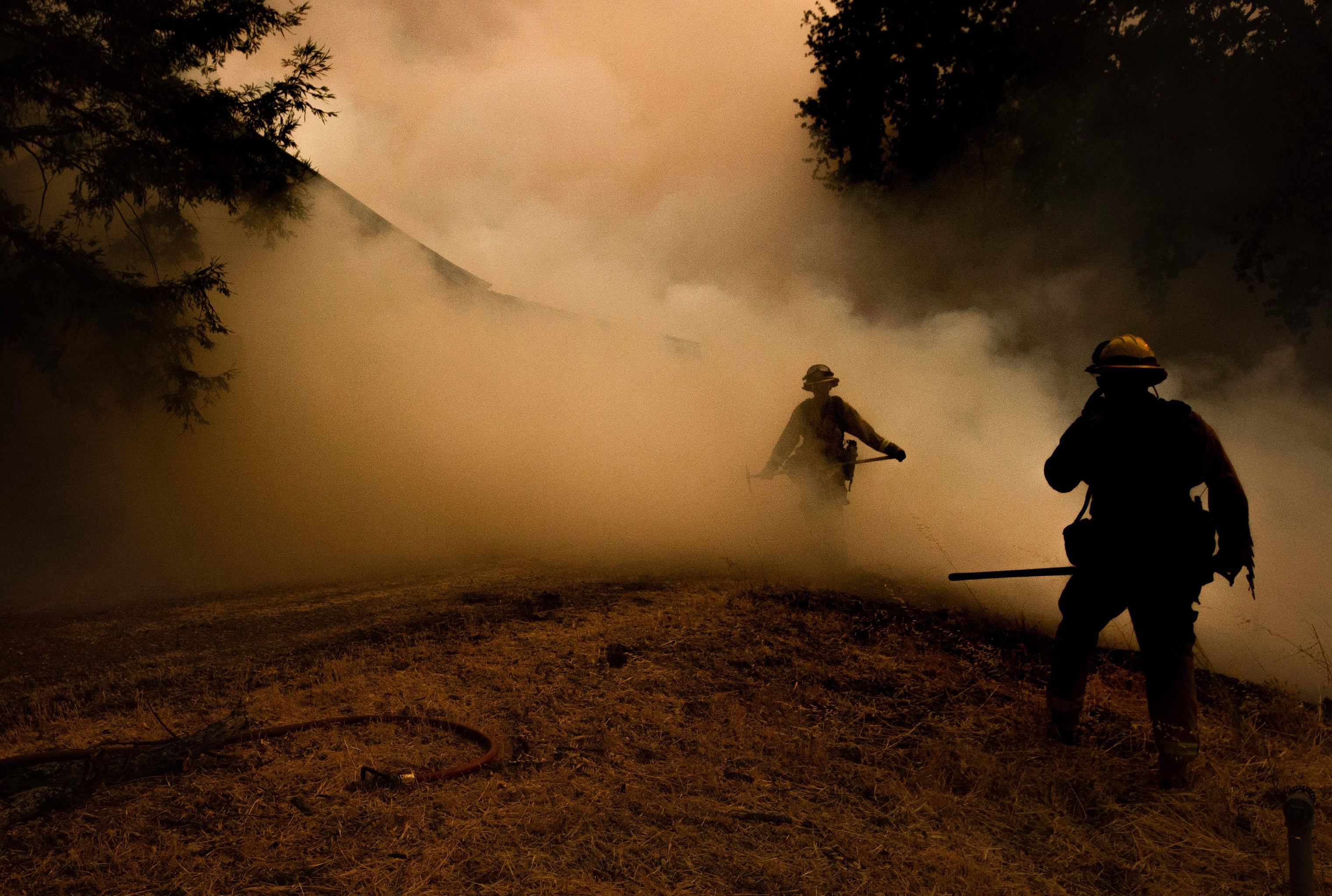 A firefighter walks through smoke as flames approach a home during the Mendocino Complex fire in Lakeport, Calif. on July 30.