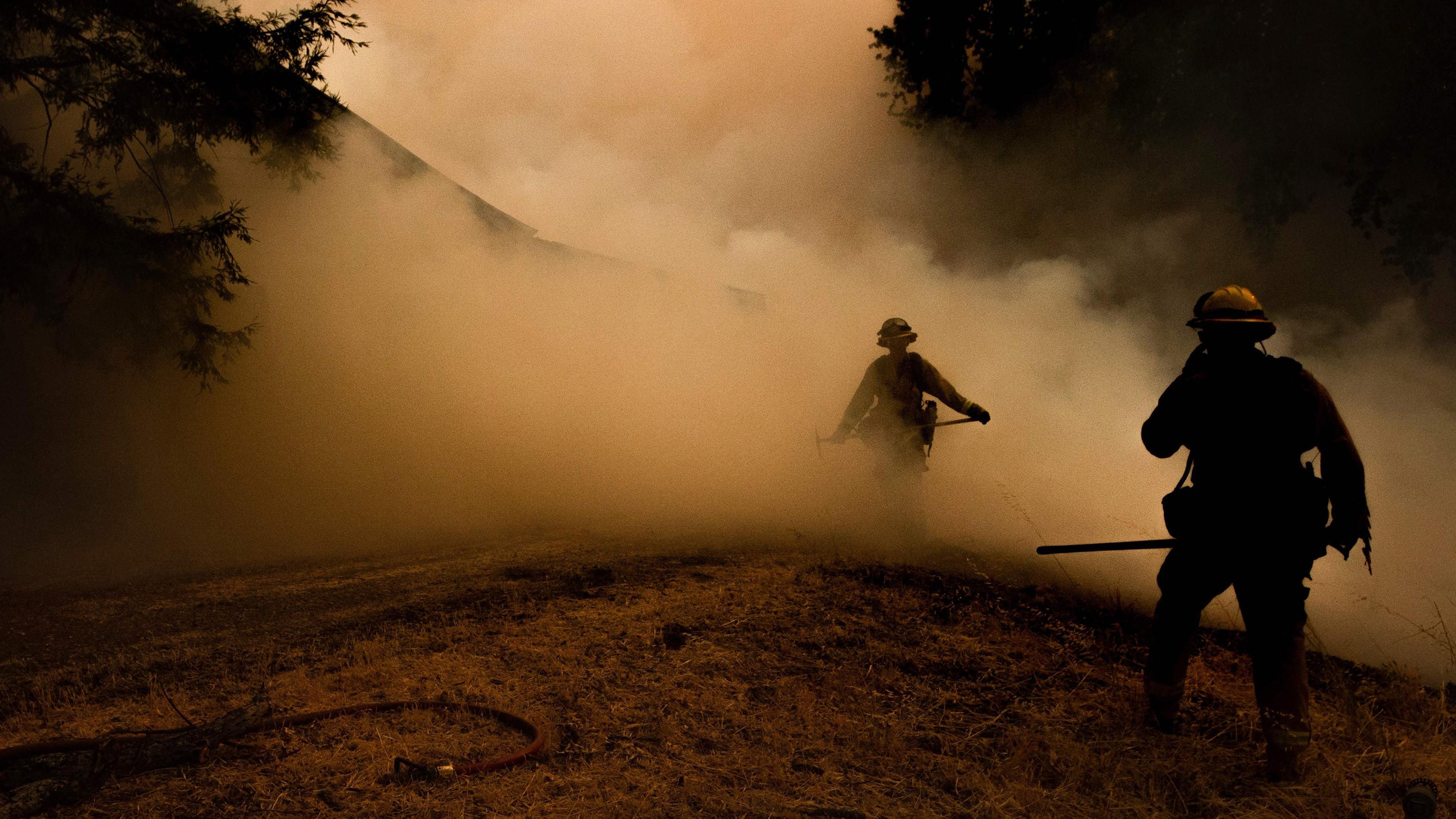A firefighter walks through smoke as flames approach a home during the Mendocino Complex fire in Lakeport, Calif. on July 30.