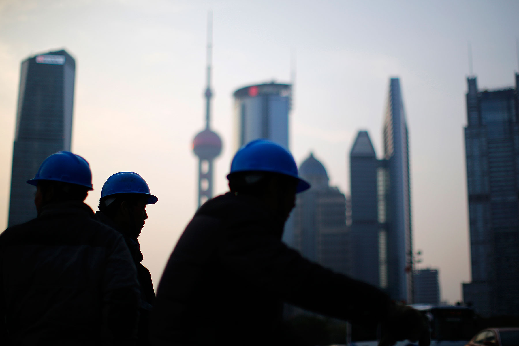 Construction workers stand on a street corner at the financial district of Pudong in Shanghai on March 11, 2014