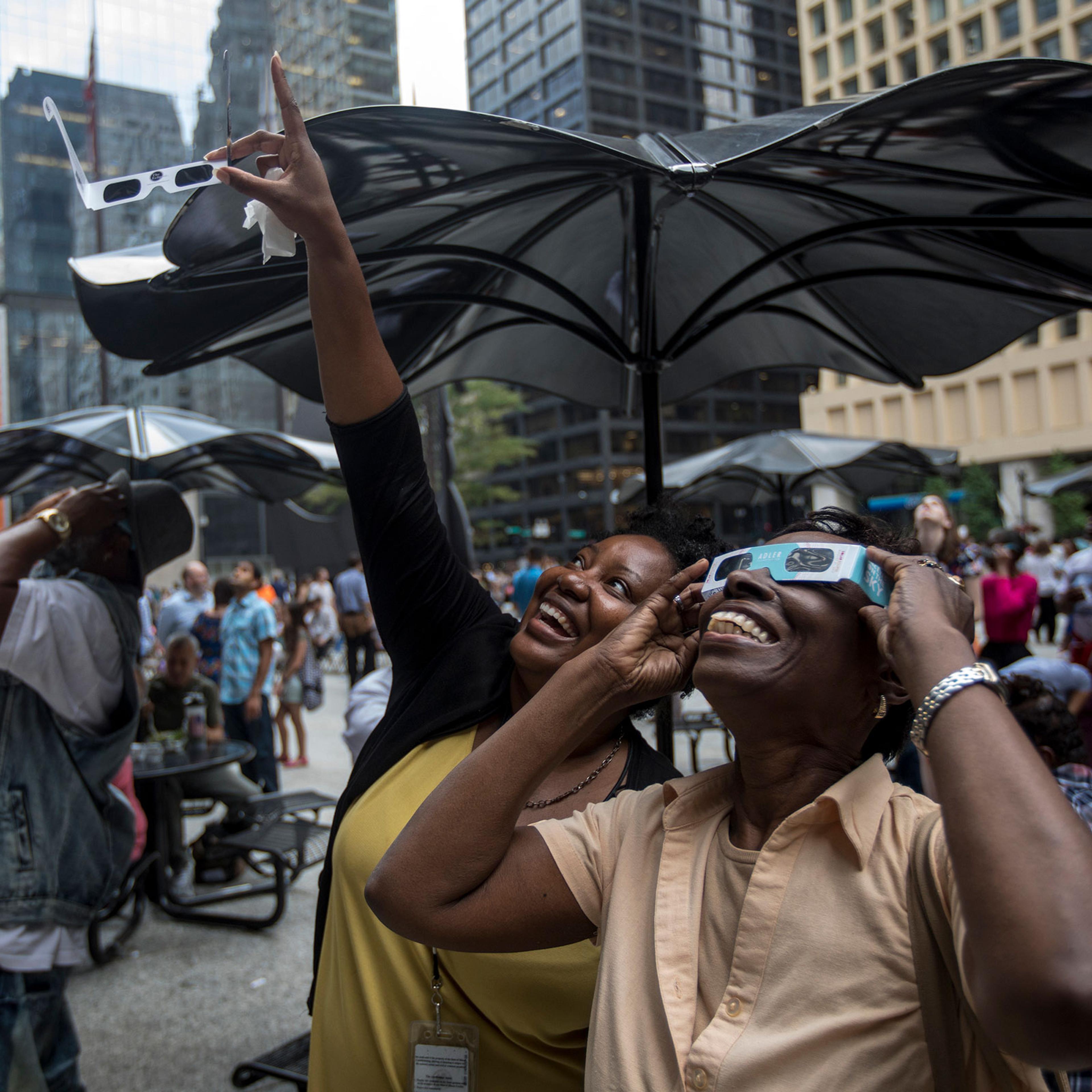 People react as the solar eclipse becomes visible through the clouds in Daley Plaza in downtown Chicago on Aug. 21, 2017.