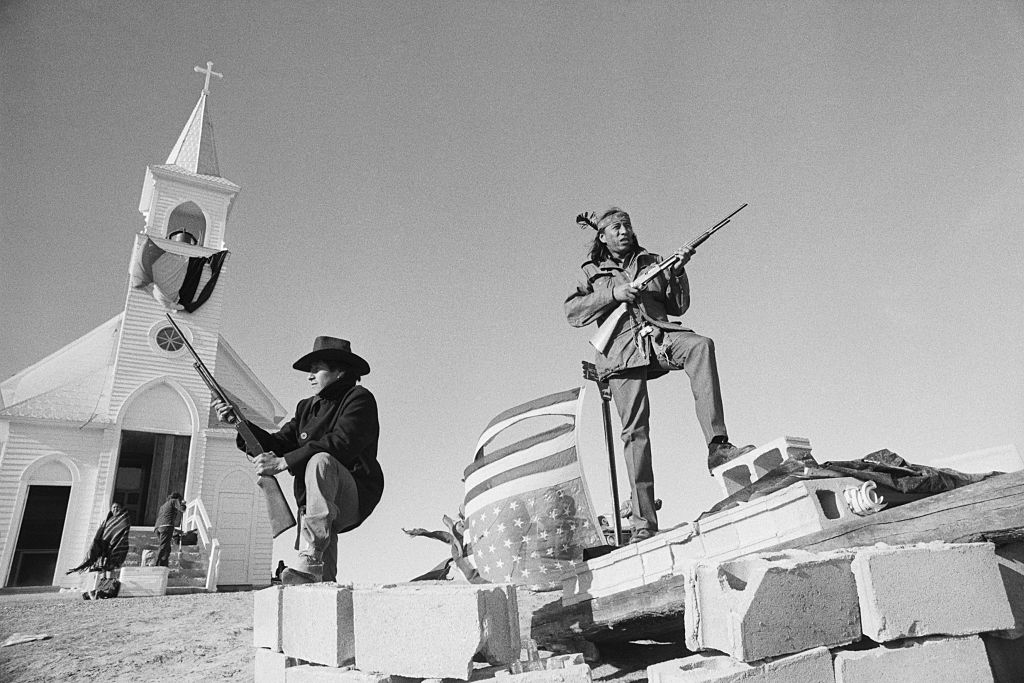 Members of the American Indian Movement and local Oglala Sioux stand guard outside the Sacred Heart Catholic Church after taking control of the town
