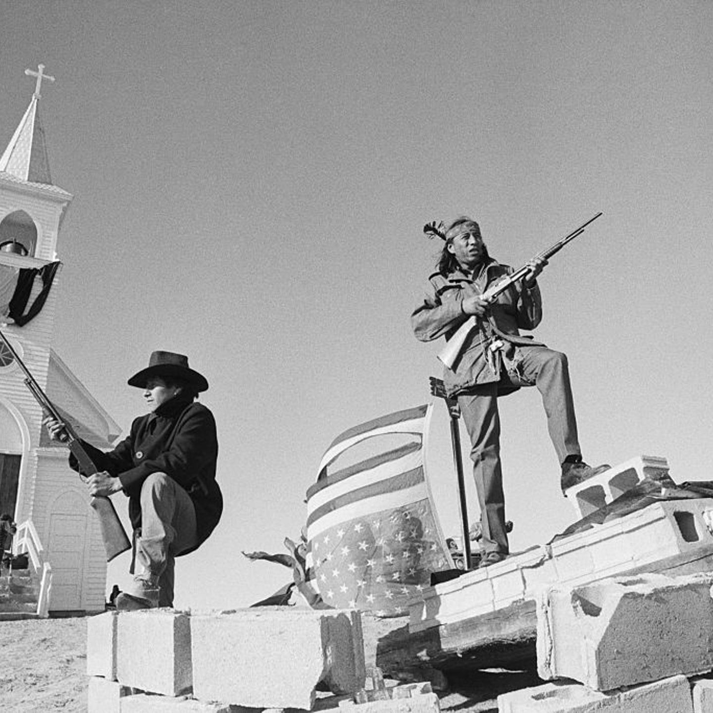 Members of the American Indian Movement and local Oglala Sioux stand guard outside the Sacred Heart Catholic Church after taking control of the town