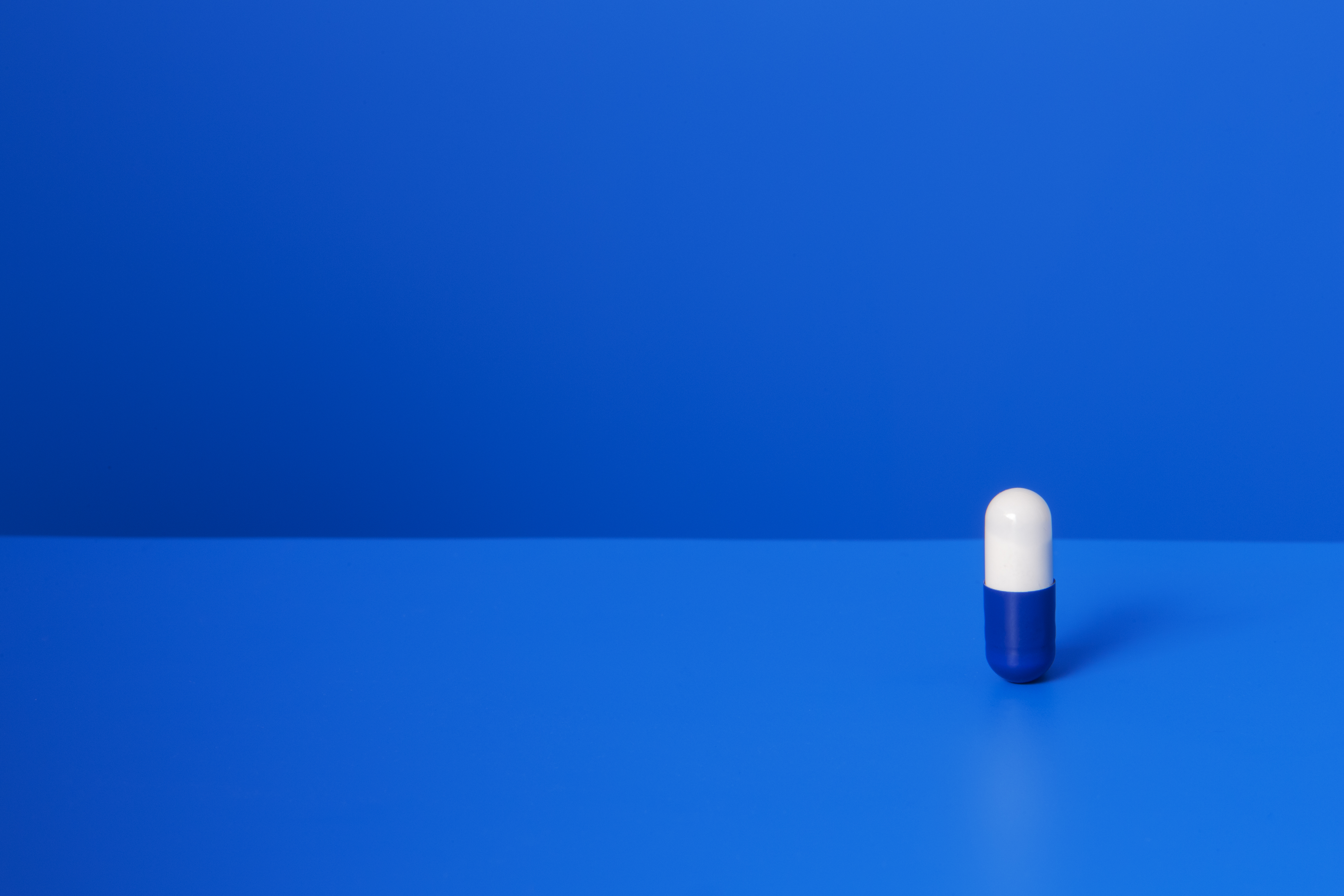 Prescription pill standing upright on blue counter TIME health