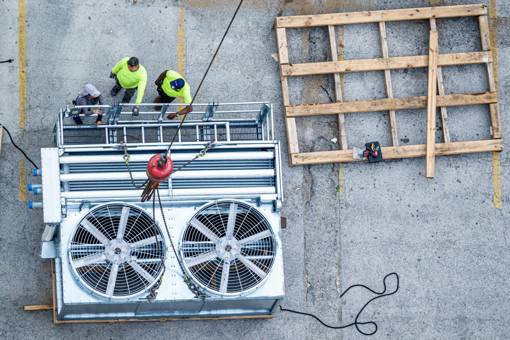 Miami Beach, Florida, construction crane placing HVAC AC air conditioner cooling tower onto rooftop.