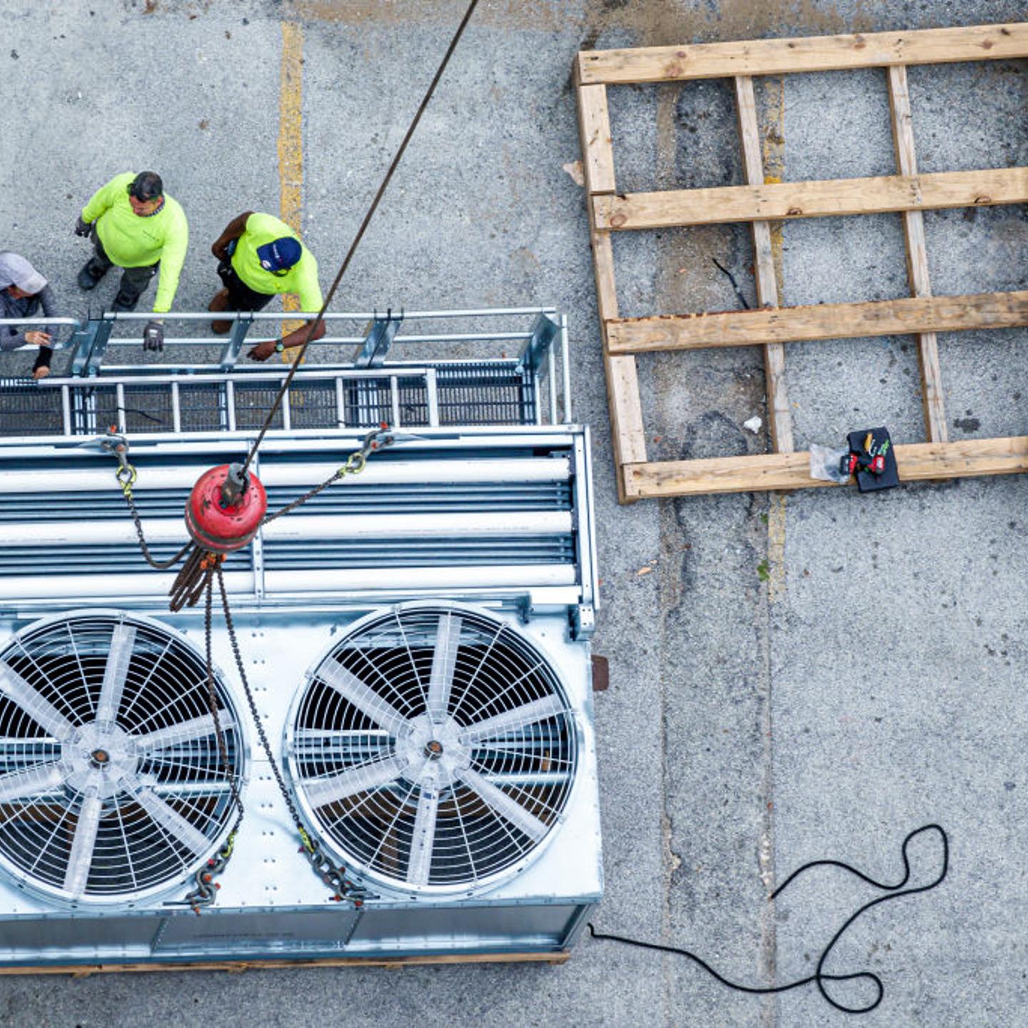 Miami Beach, Florida, construction crane placing HVAC AC air conditioner cooling tower onto rooftop.