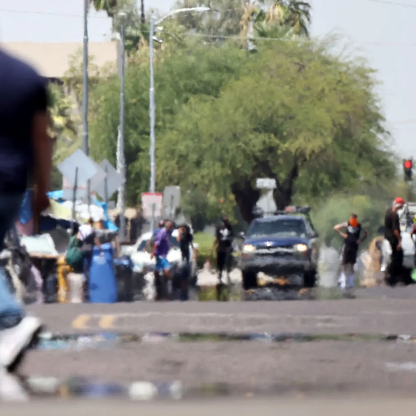 Heat waves shimmer, causing visual distortion, as people walk in the 'The Zone', Phoenix's largest homeless encampment, amid the city's worst heat wave on record on July 25, 2023 in Phoenix, Arizona.
