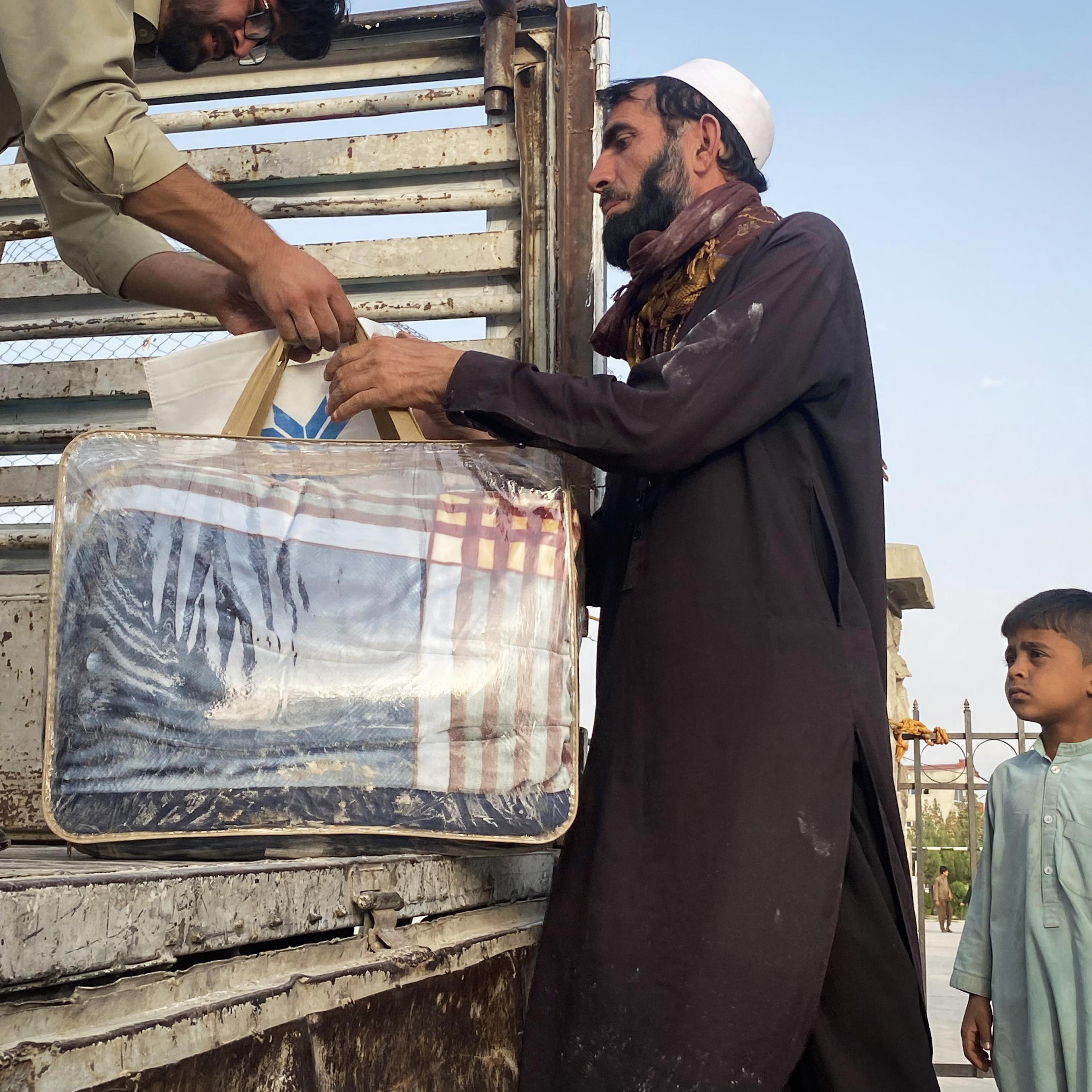 A resident of Logar Province, Afghanistan, collects a blanket from a staff member of Aseel on Oct. 2, 2021