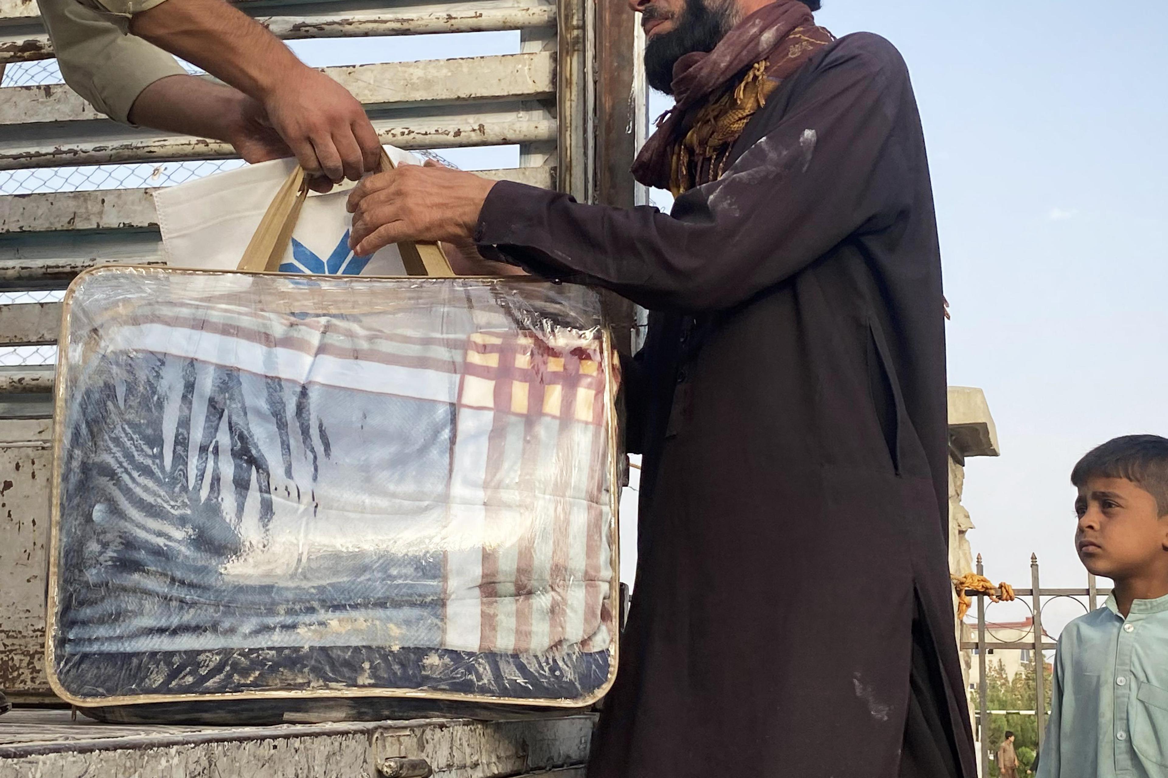 A resident of Logar Province, Afghanistan, collects a blanket from a staff member of Aseel on Oct. 2, 2021