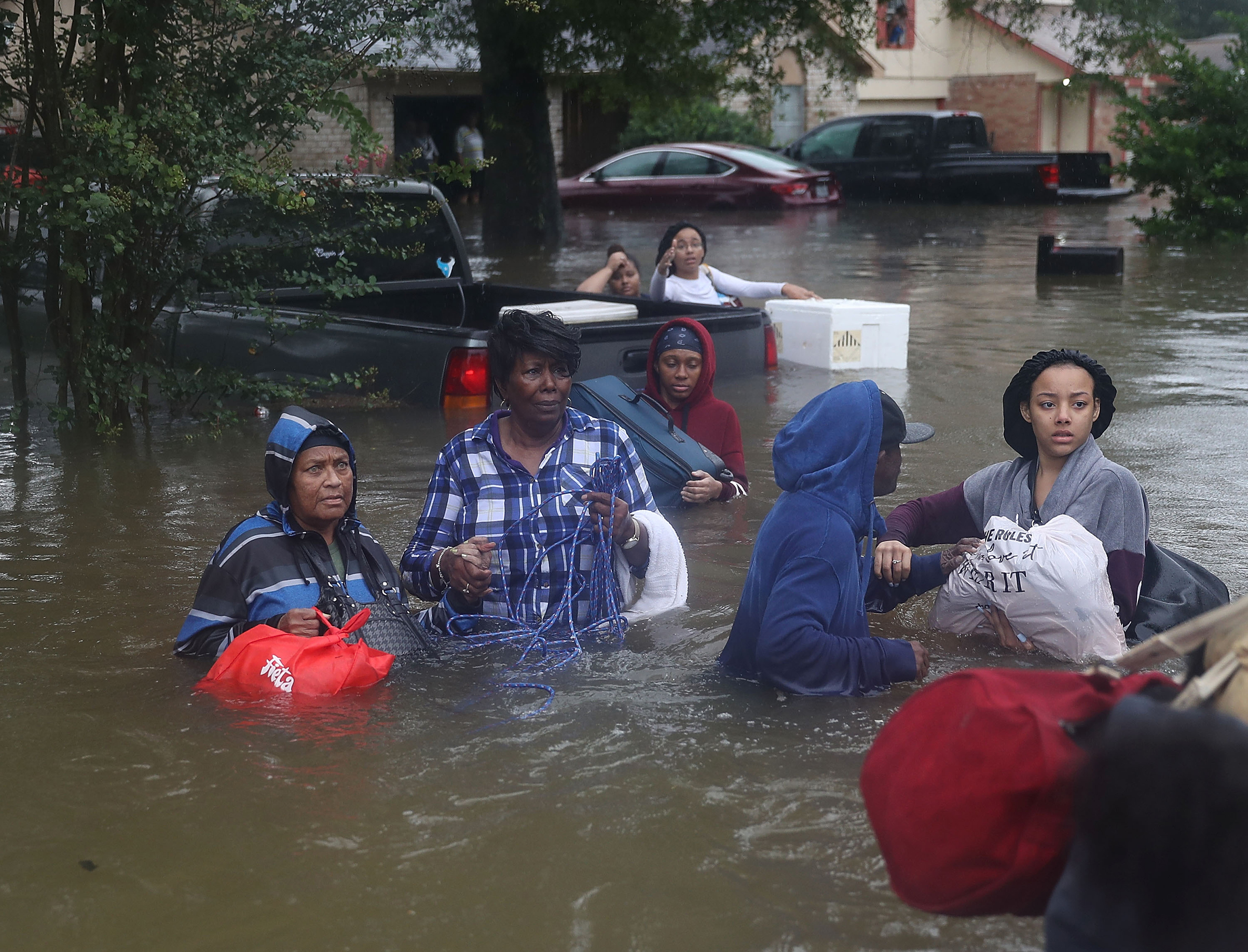 People walk down a flooded street as they evacuate their homes after the area was inundated with flooding from Hurricane Harvey on Aug. 28, 2017 in Houston.