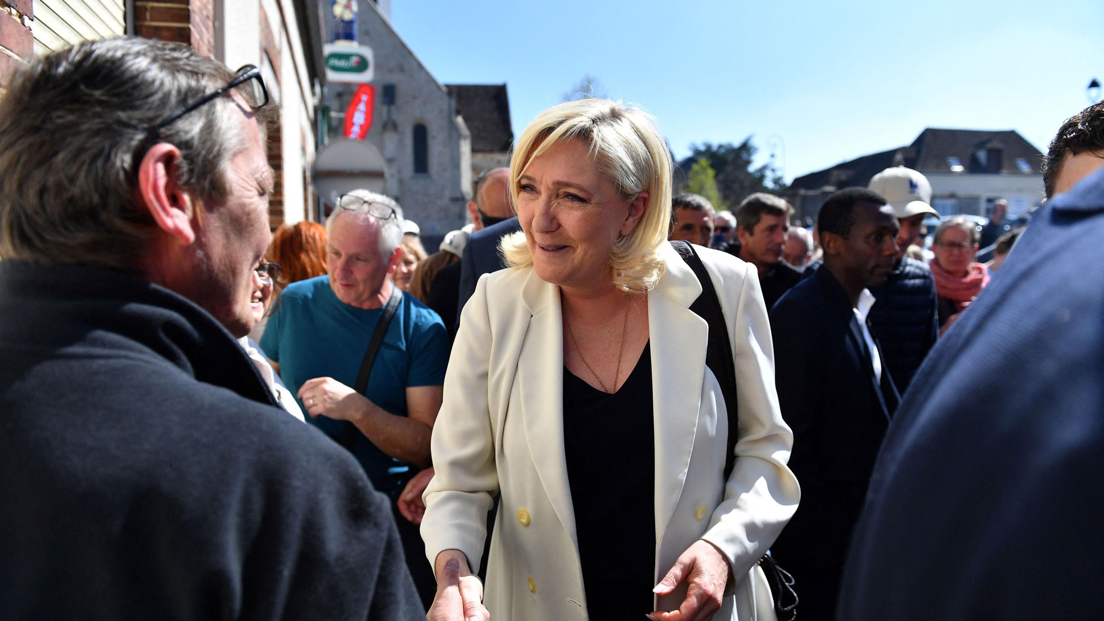 Marine Le Pen shakes hands with a member of the public during a campaign visit