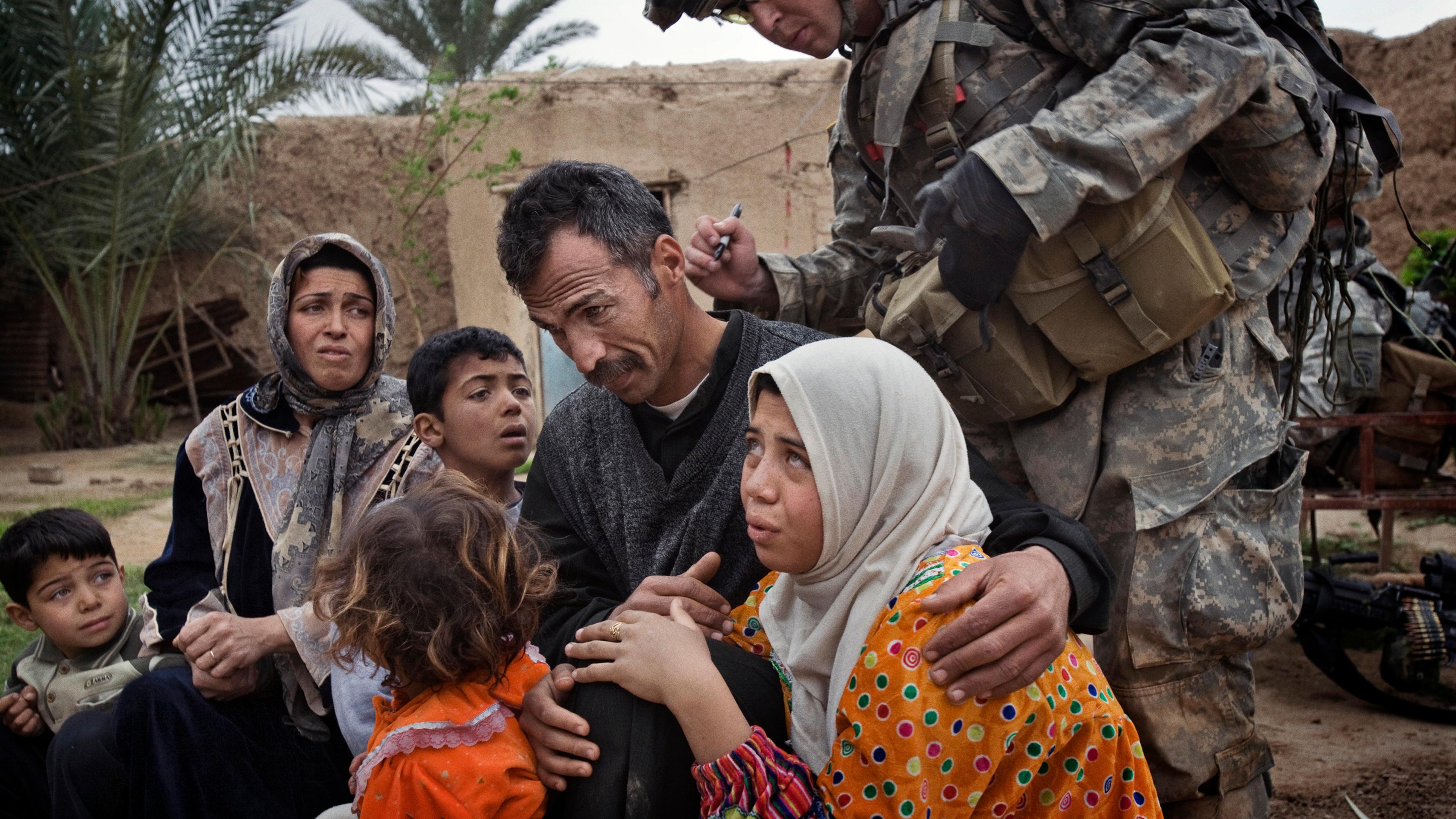 A U.S. soldier marks the neck of a man with identifying numbers. The numbering system allowed U.S. troops to tell whether anyone was moving about the village, despite a lockdown, Qubah, Iraq, March 24, 2007.