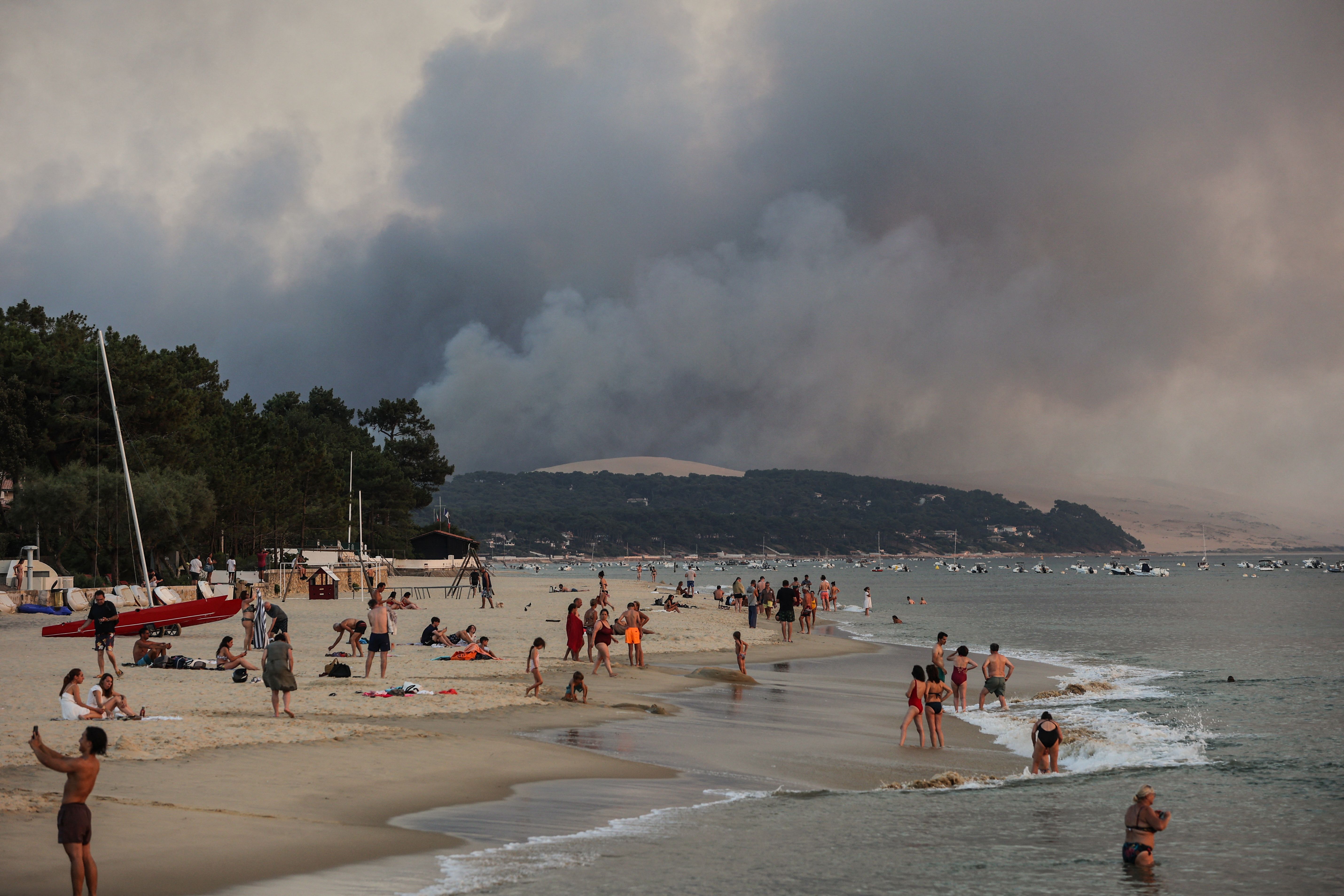 Smoke rises from a forest fire behind beachgoers in Arcachon, France, on July 18, 2022, when temperatures topped 100° F.