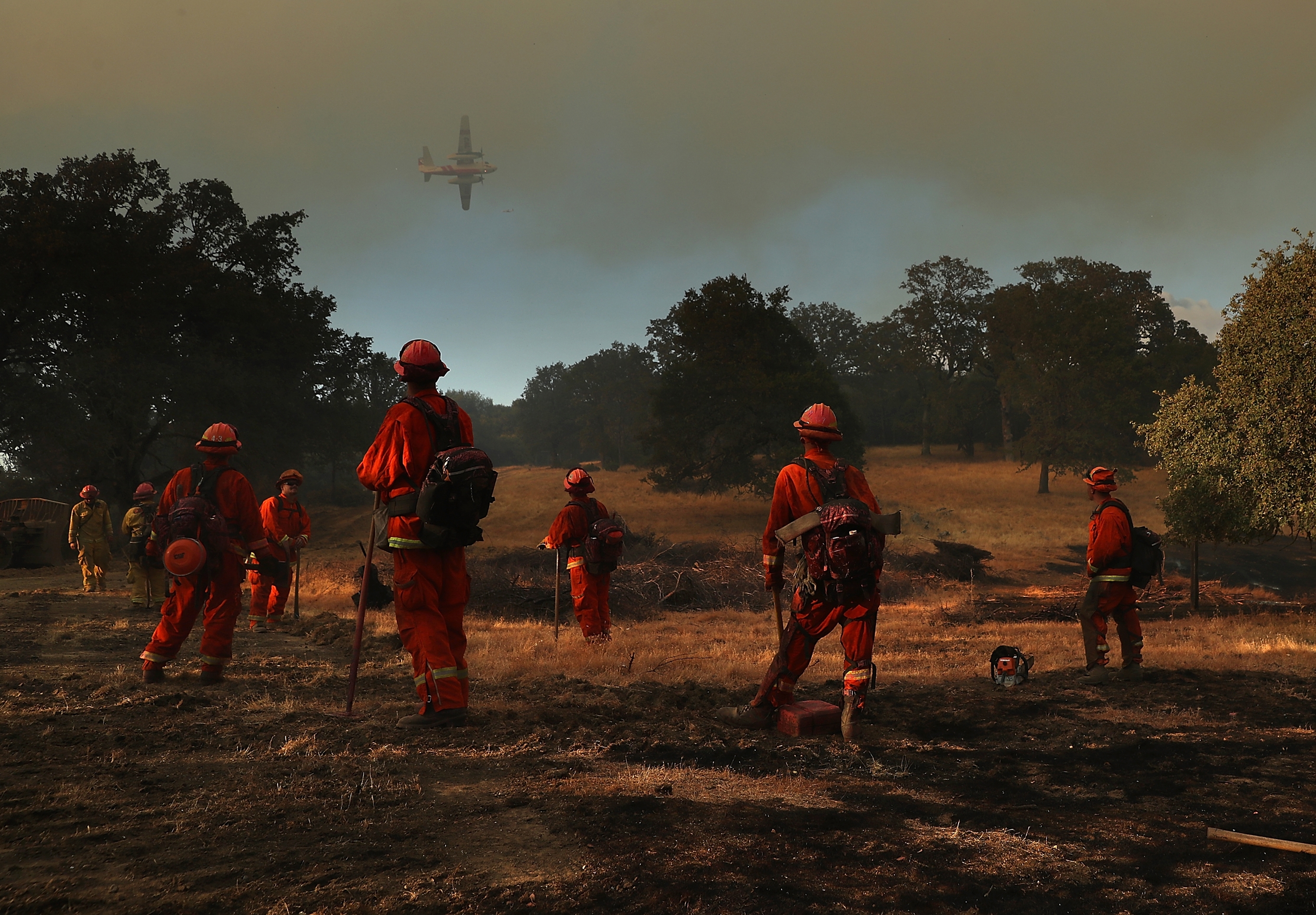 Inmate firefighters look on as a firefighting aircraft prepares to drop fire retardant ahead of the River Fire as it burns through a canyon in Lakeport, Calif. on on Aug. 1.