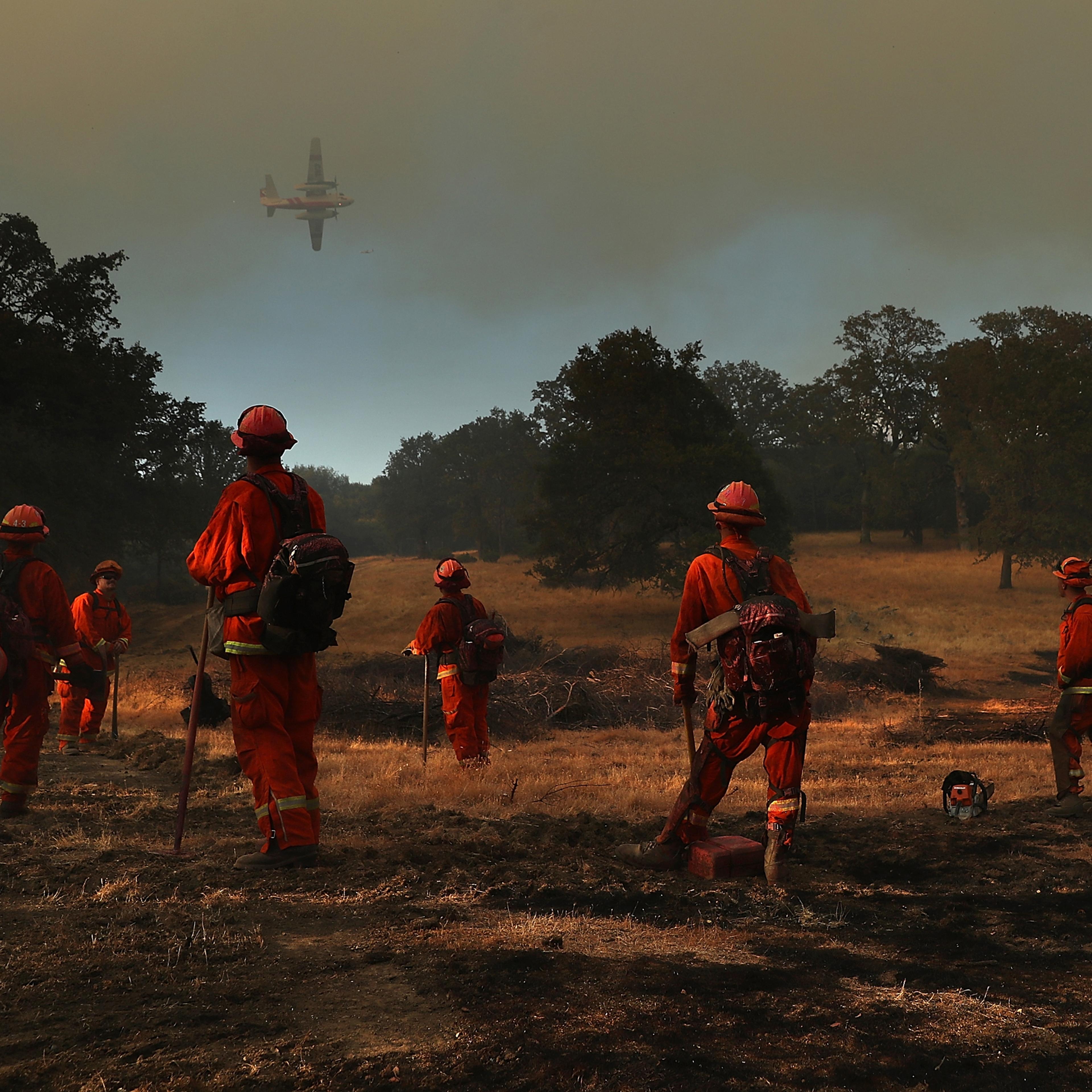 Inmate firefighters look on as a firefighting aircraft prepares to drop fire retardant ahead of the River Fire as it burns through a canyon in Lakeport, Calif. on on Aug. 1.