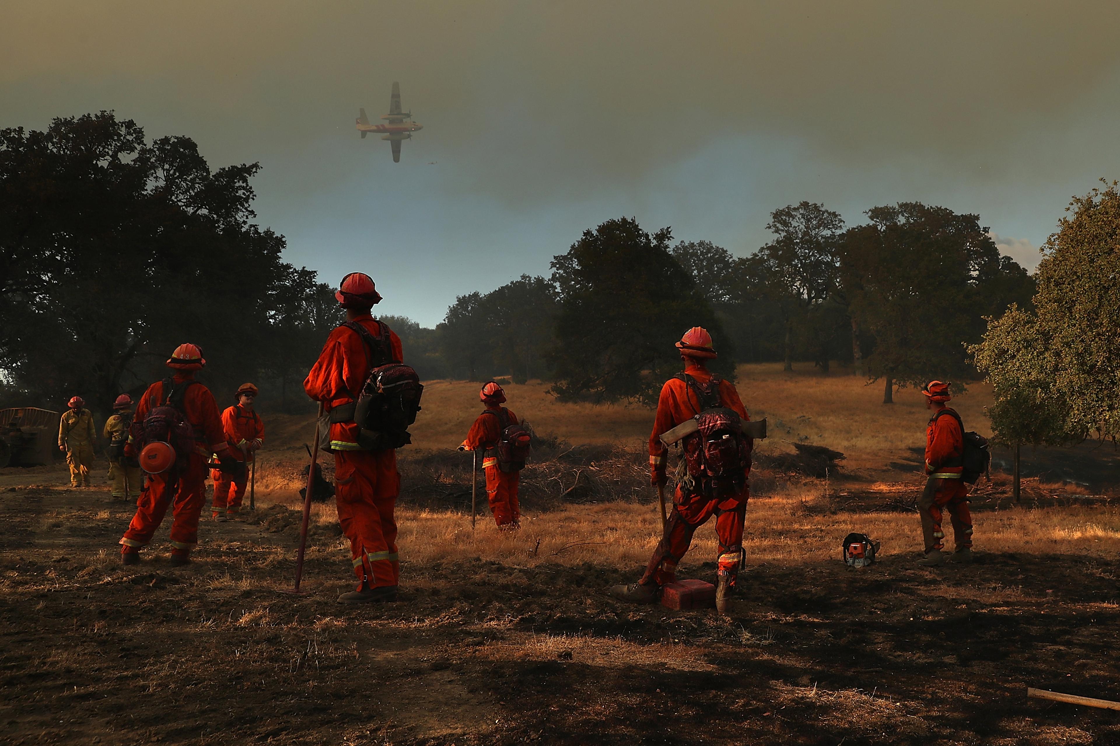 Inmate firefighters look on as a firefighting aircraft prepares to drop fire retardant ahead of the River Fire as it burns through a canyon in Lakeport, Calif. on on Aug. 1.