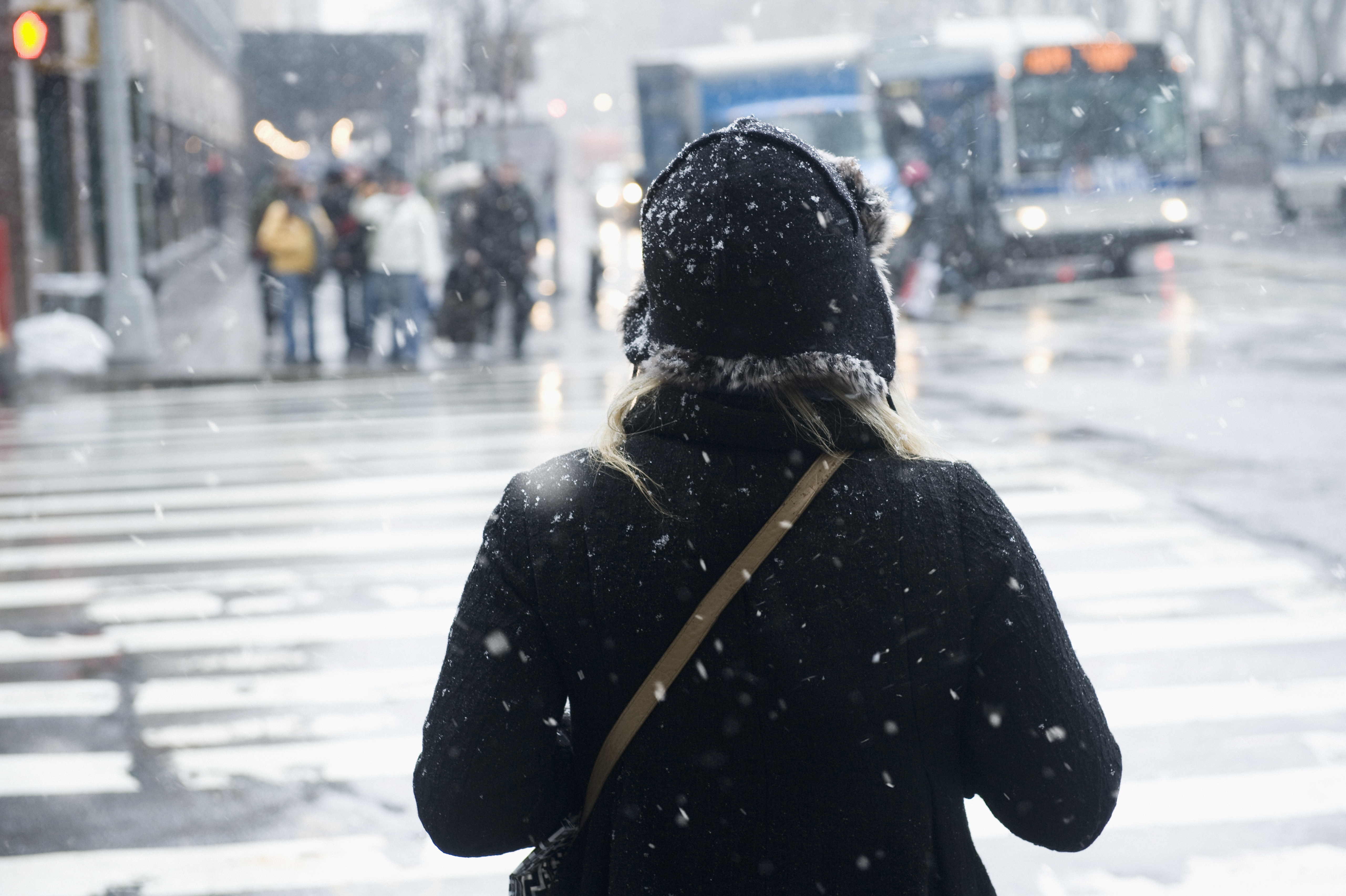 Young woman about to cross the street in snow