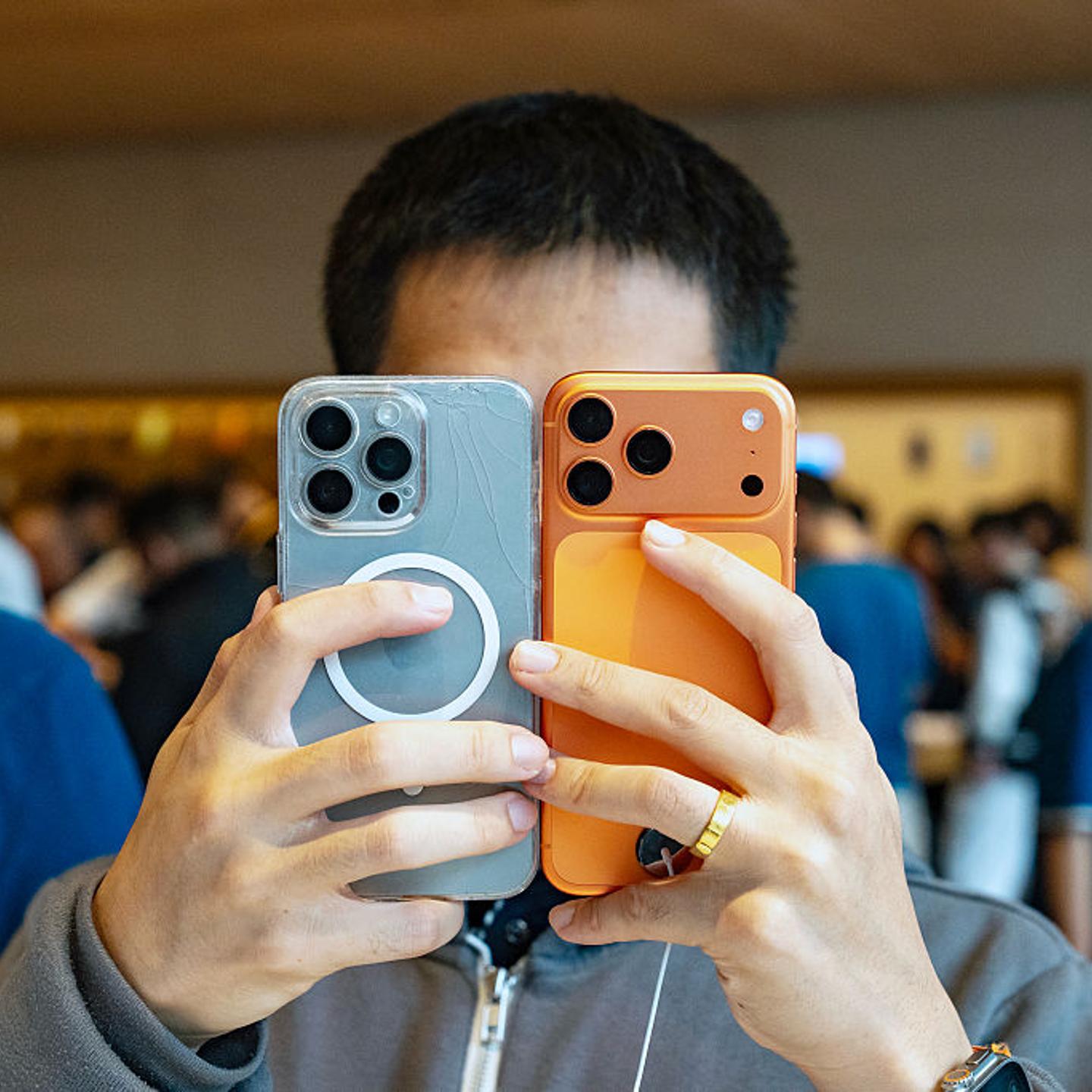 A person holds two smartphones up to their face.