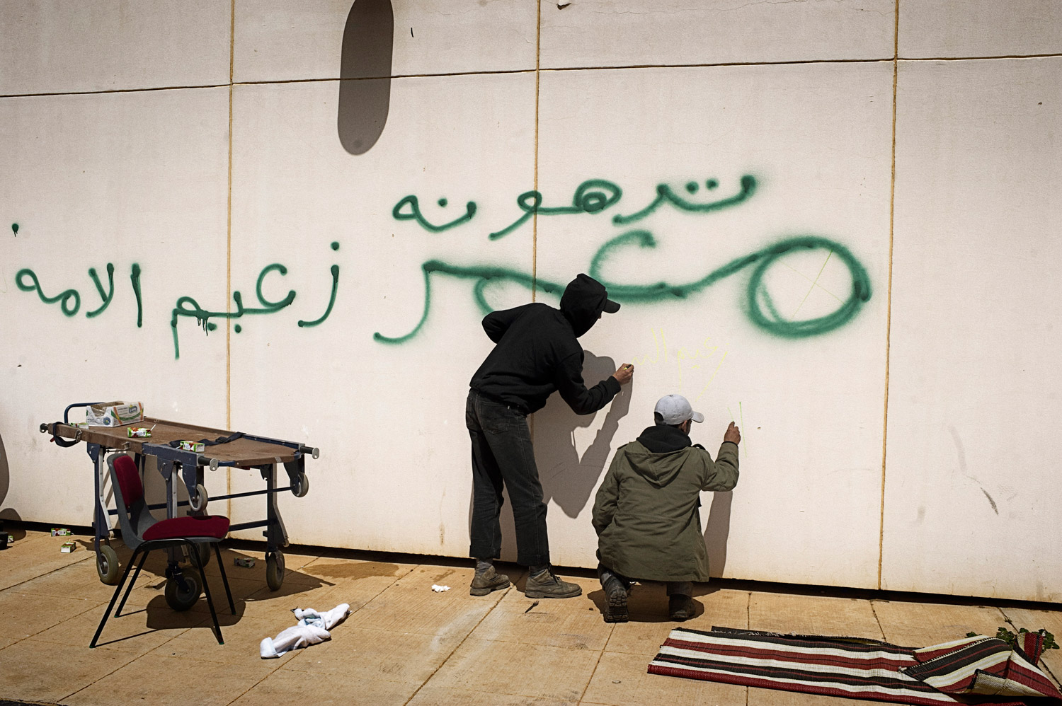 Libyan rebels scrawl graffiti on a wall near a hospital in Ras Lanuf, March 27, 2011. The wall was previously defaced, in green, by Gaddafi troops.