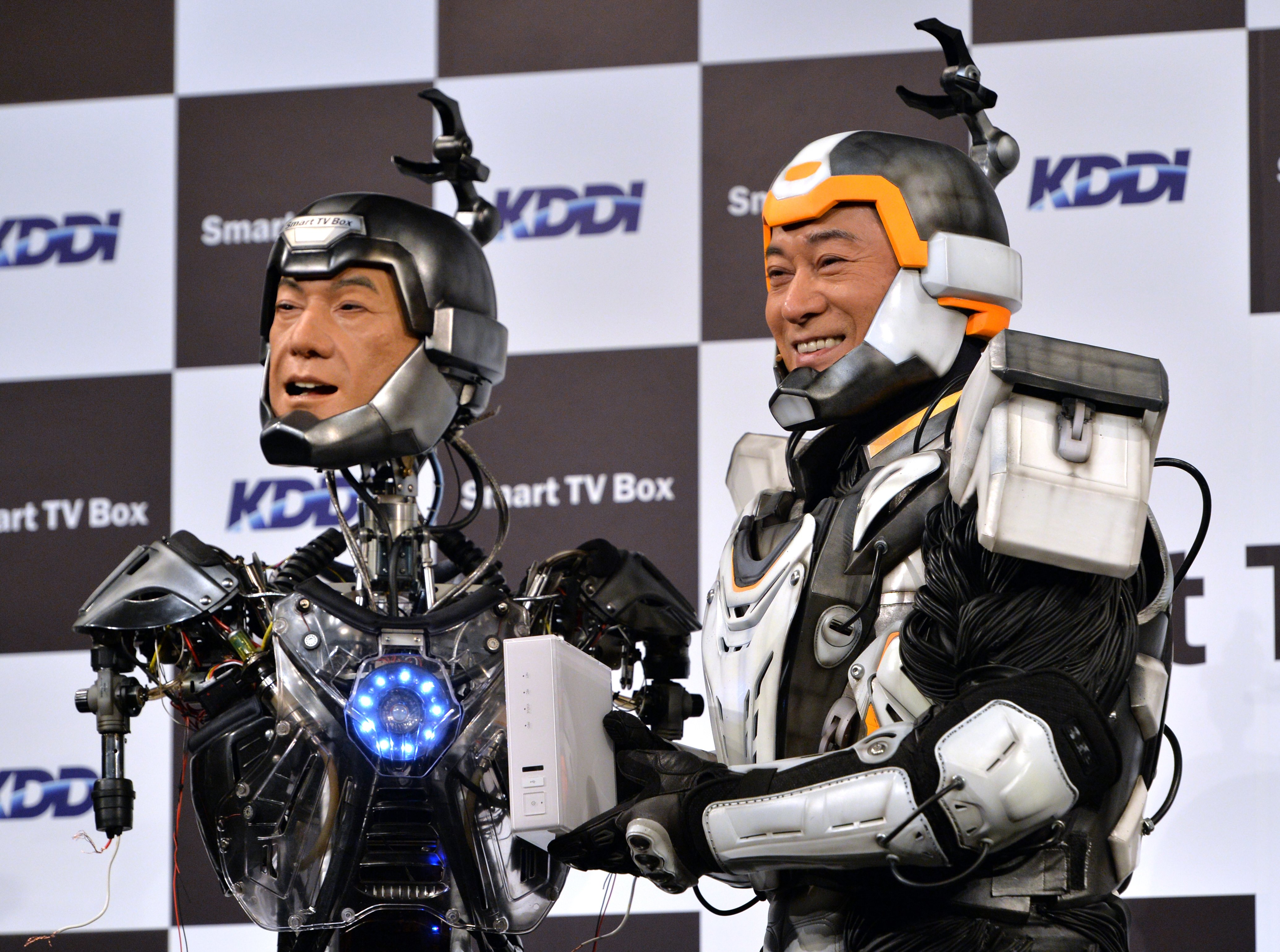 Japanese actor Ken Matsudaira clad in a robot suit, smiles with an android robot in his likeness called "Real Android Matsuken" at a press presentation in Tokyo on November 19, 2013.