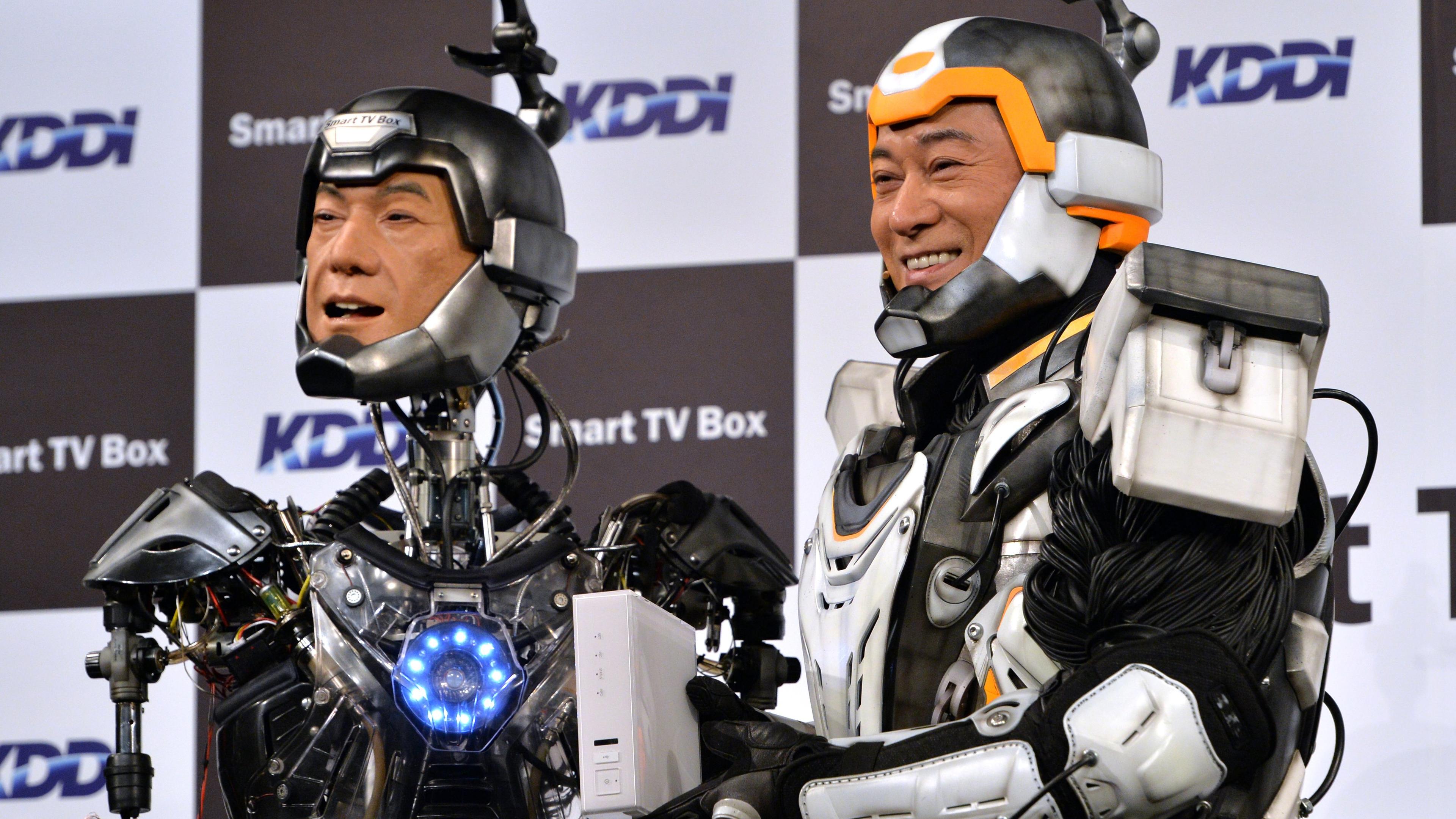 Japanese actor Ken Matsudaira clad in a robot suit, smiles with an android robot in his likeness called "Real Android Matsuken" at a press presentation in Tokyo on November 19, 2013.