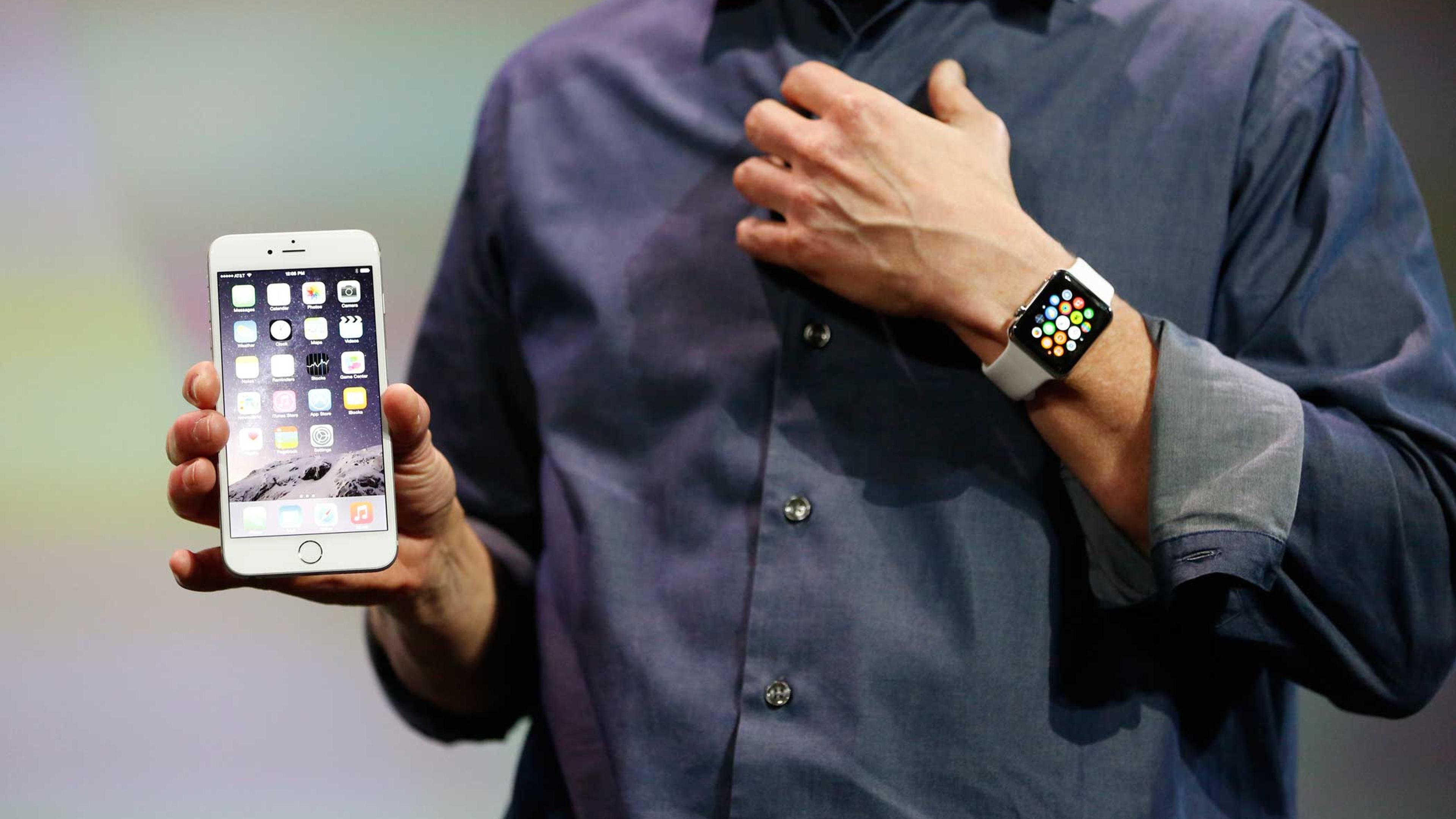 Apple CEO Tim Cook wears the Apple Watch and shows the iPhone 6 Plus during an Apple event at the Flint Center in Cupertino