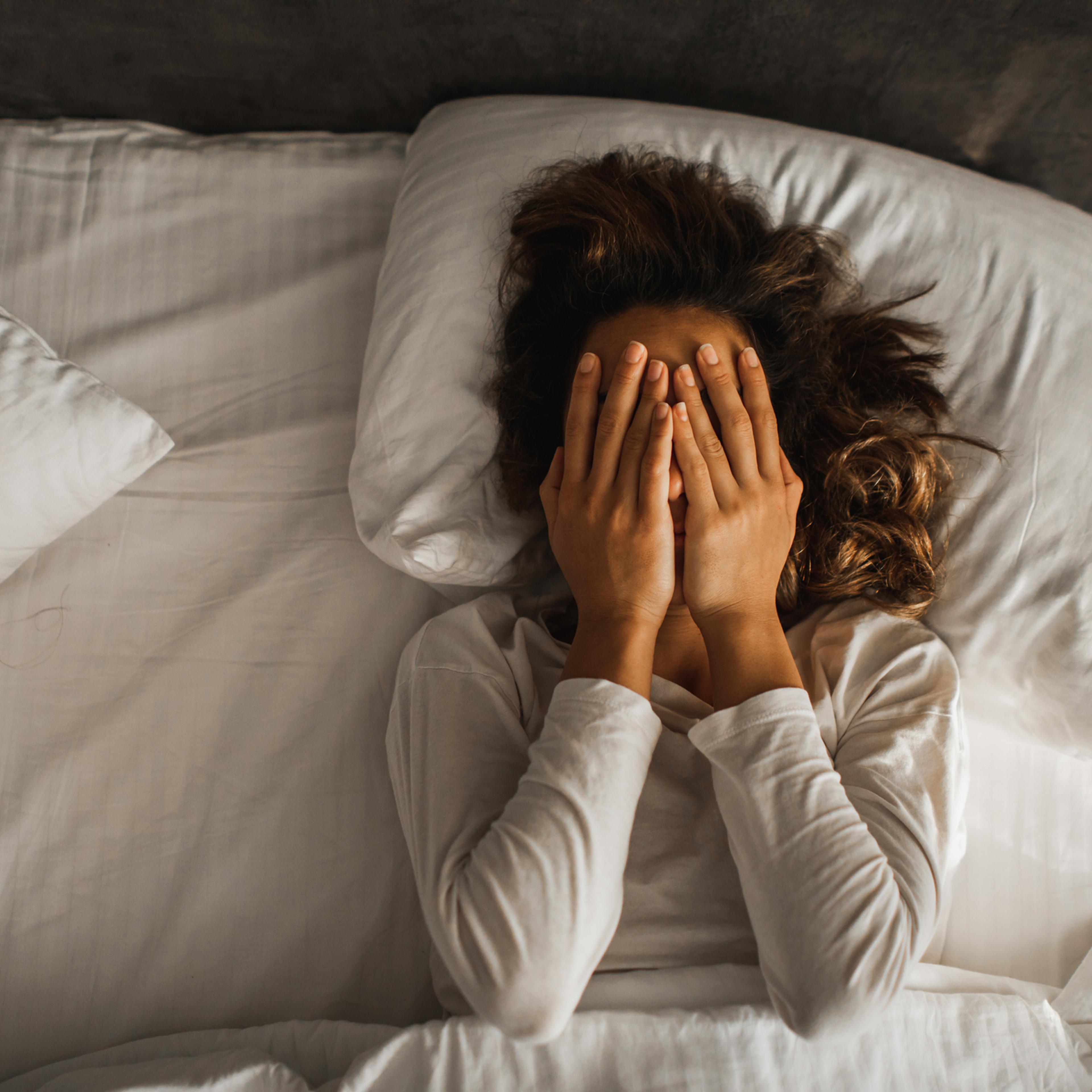 Woman in depression closed face with hands and crying in bed. Melancholy mood, mental health. Life problems