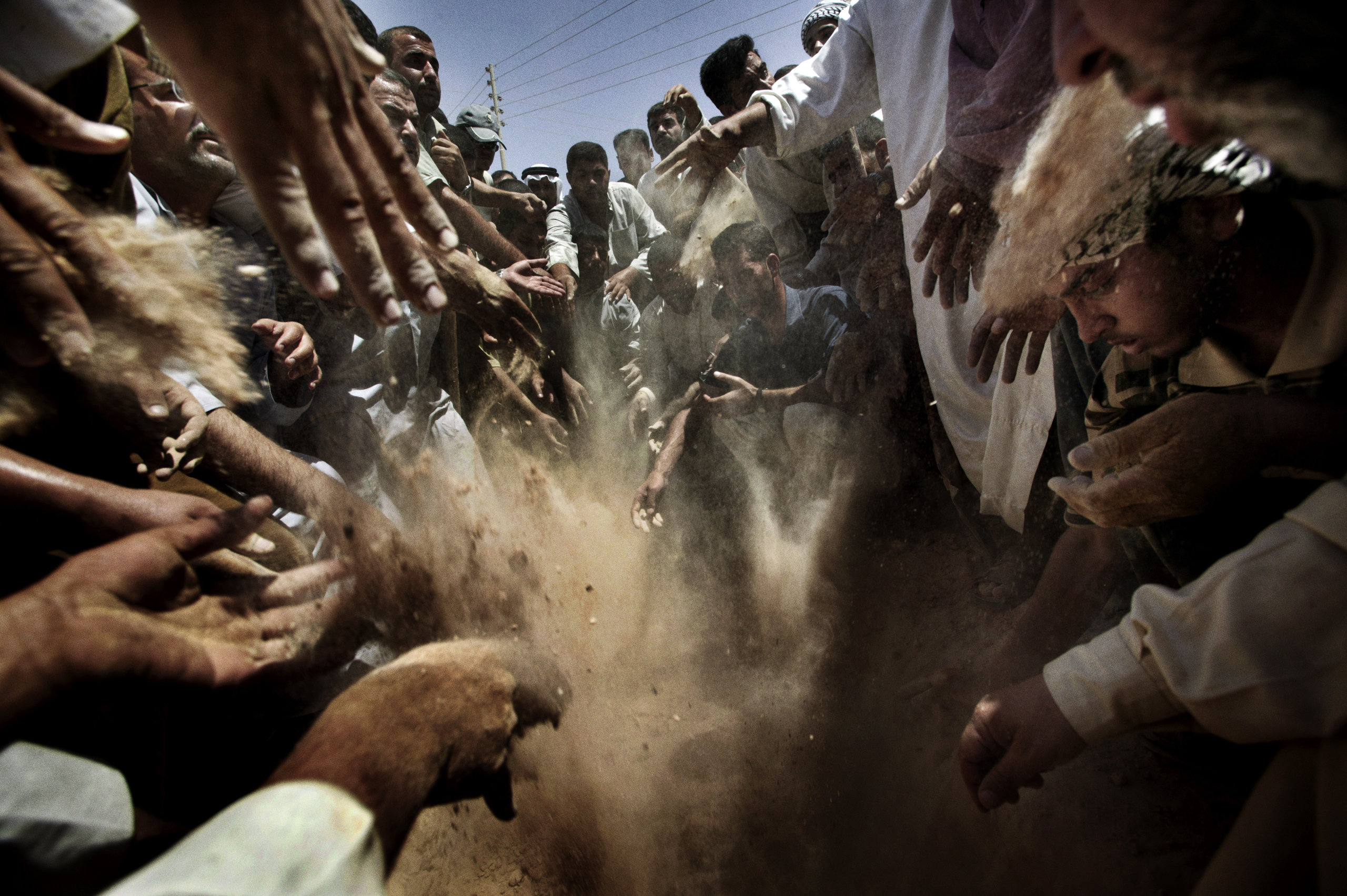 Citizens of Owja and Tikrit , Iraq gather at the cemetery outside Saddam Hussein's ancestral village to bury the bodies of Uday, Qusay and Qusay's son Mustafa, Aug. 2, 2003.
