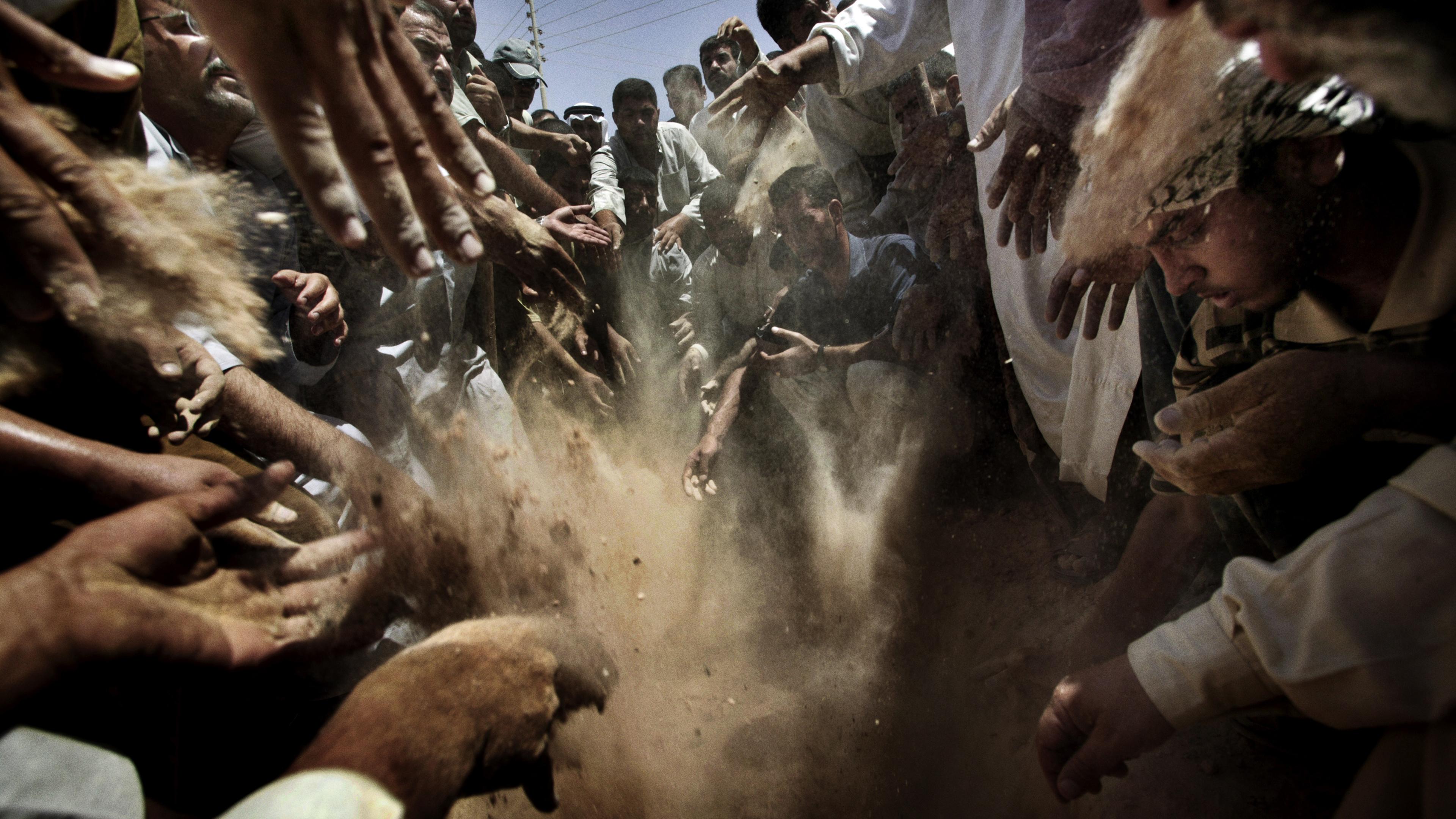 Citizens of Owja and Tikrit , Iraq gather at the cemetery outside Saddam Hussein's ancestral village to bury the bodies of Uday, Qusay and Qusay's son Mustafa, Aug. 2, 2003.